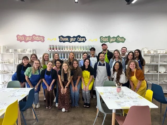 People painting watercolor pictures of lemons and lemon branches at a round table with drinks and art supplies.