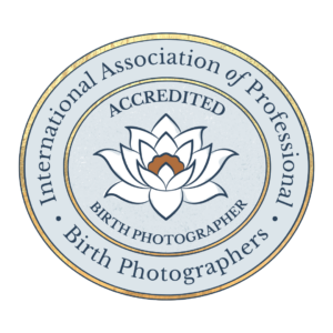 A circular badge with a lotus flower in the center, surrounded by text that reads 'International Association of Professional Birth Photographers,' 'Accredited,' and 'Birth Photographers.'