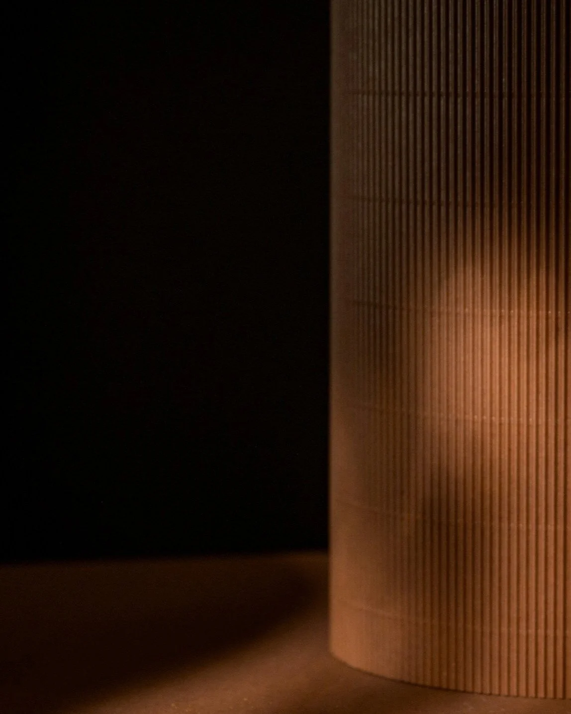 Close-up of a wooden cylindrical object with vertical grooves, placed on a surface in a dimly lit setting.