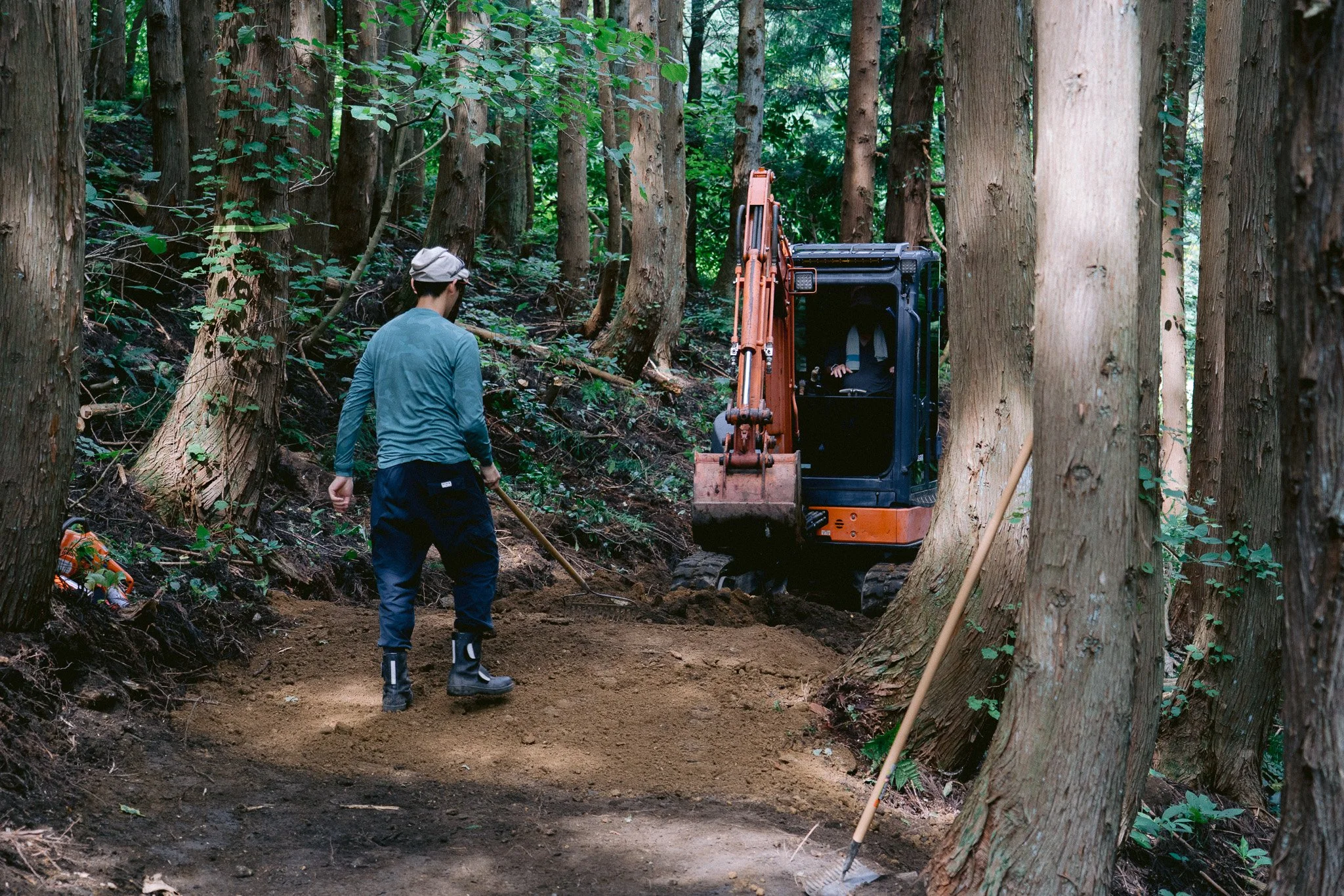 森の中のトレイルでミニショベルを使ってMTBコースを施工する作業風景