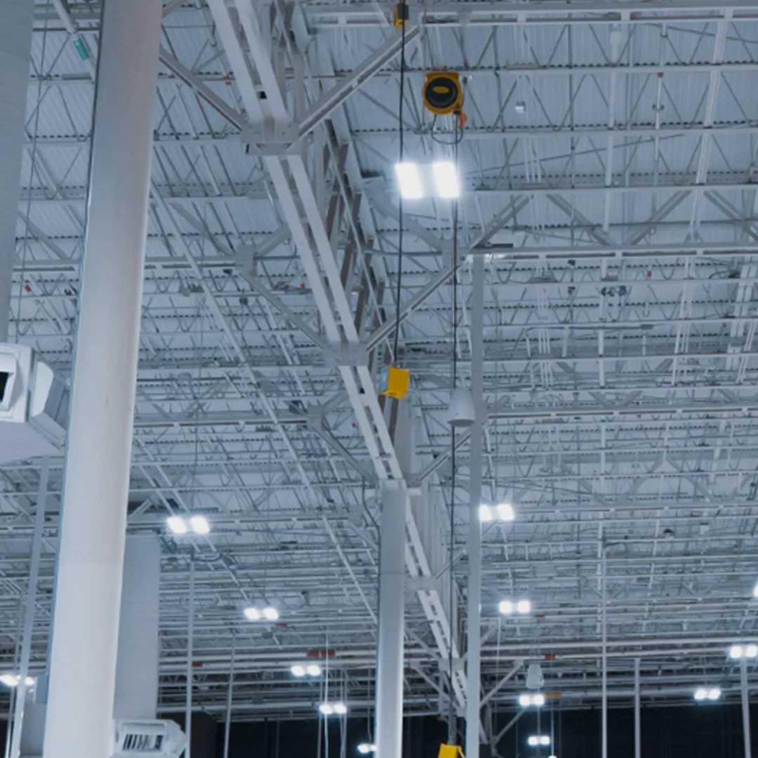 Interior de una fábrica o almacén con techo industrial, estructuras metálicas y luces brillantes.