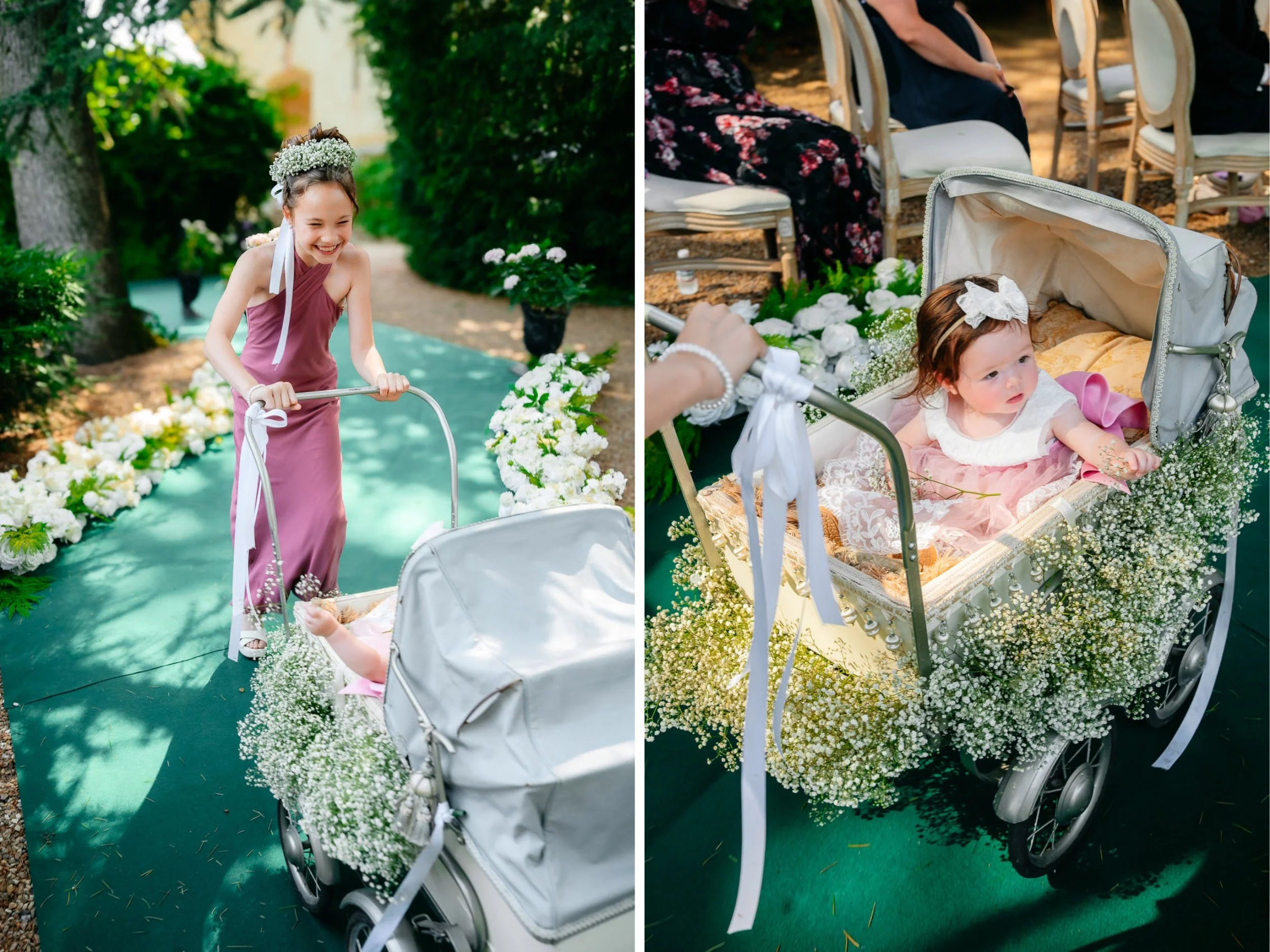 A young girl wearing a floral crown and a pink dress is riding a decorated stroller down a pathway surrounded by flowers and greenery. The stroller is adorned with white flowers and ribbons, with seated guests in the background.