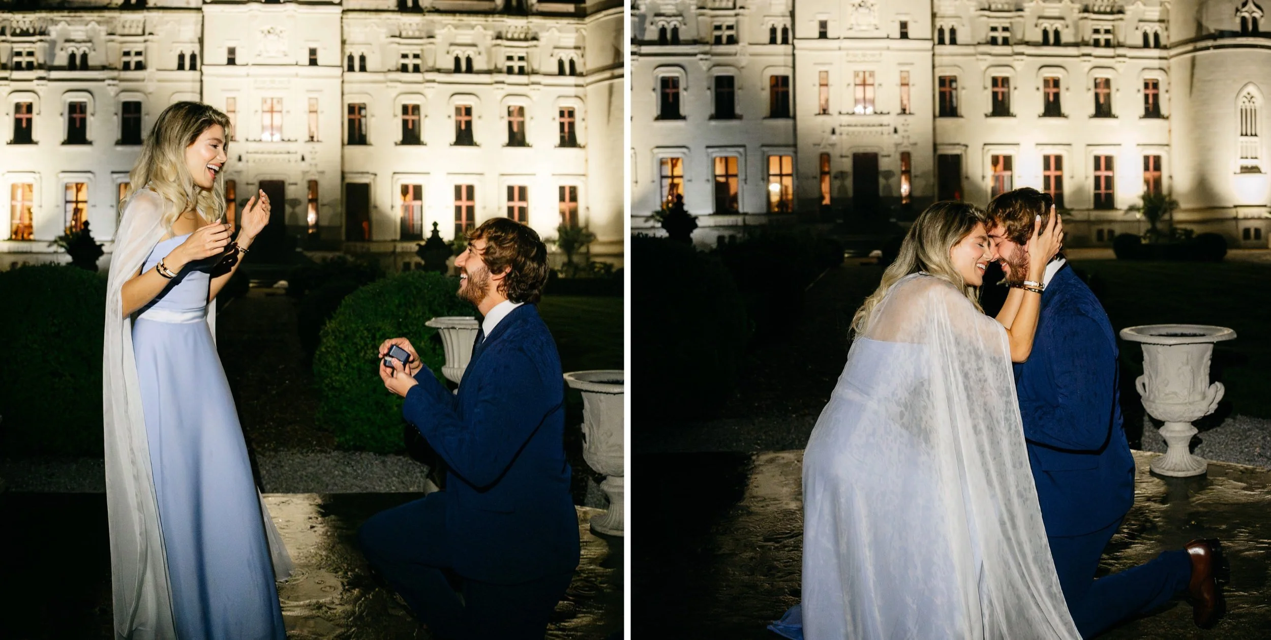 A man is kneeling on one knee, proposing to a woman in front of a large, illuminated building at night. The woman is smiling and looking down at the man, who is holding a small box, presumably with a ring inside. The scene appears joyful and romantic