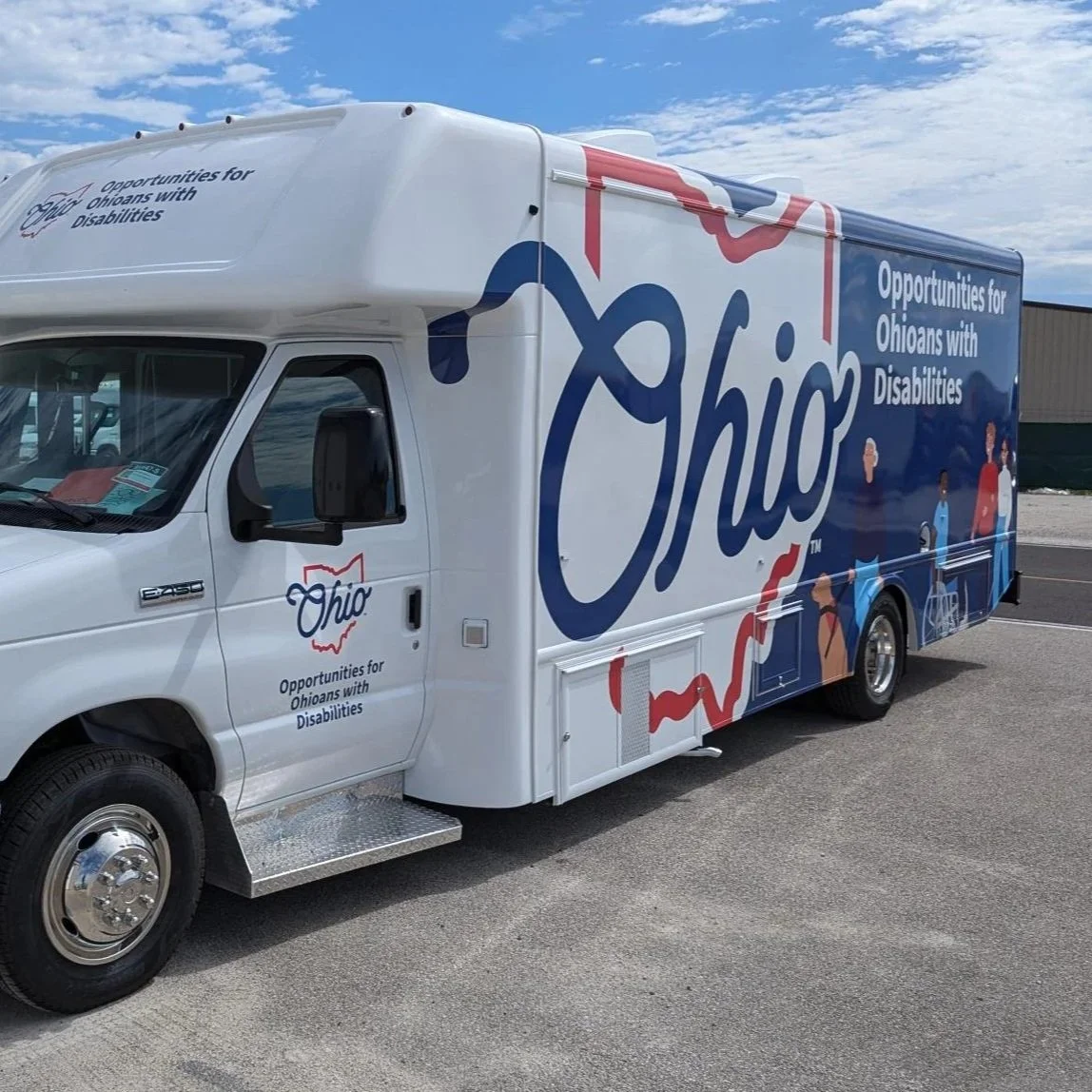 A white truck with Ohio branding, featuring the slogan 'Opportunities for Ohioans with Disabilities,' parked outdoors with a clear sky in the background.
