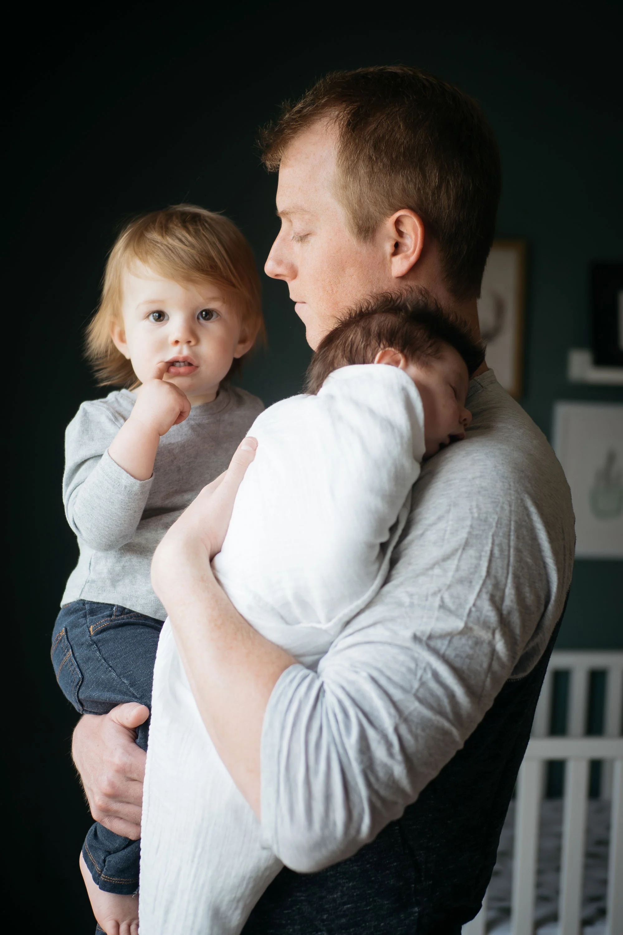 A man holding a young boy and a girl in a room.