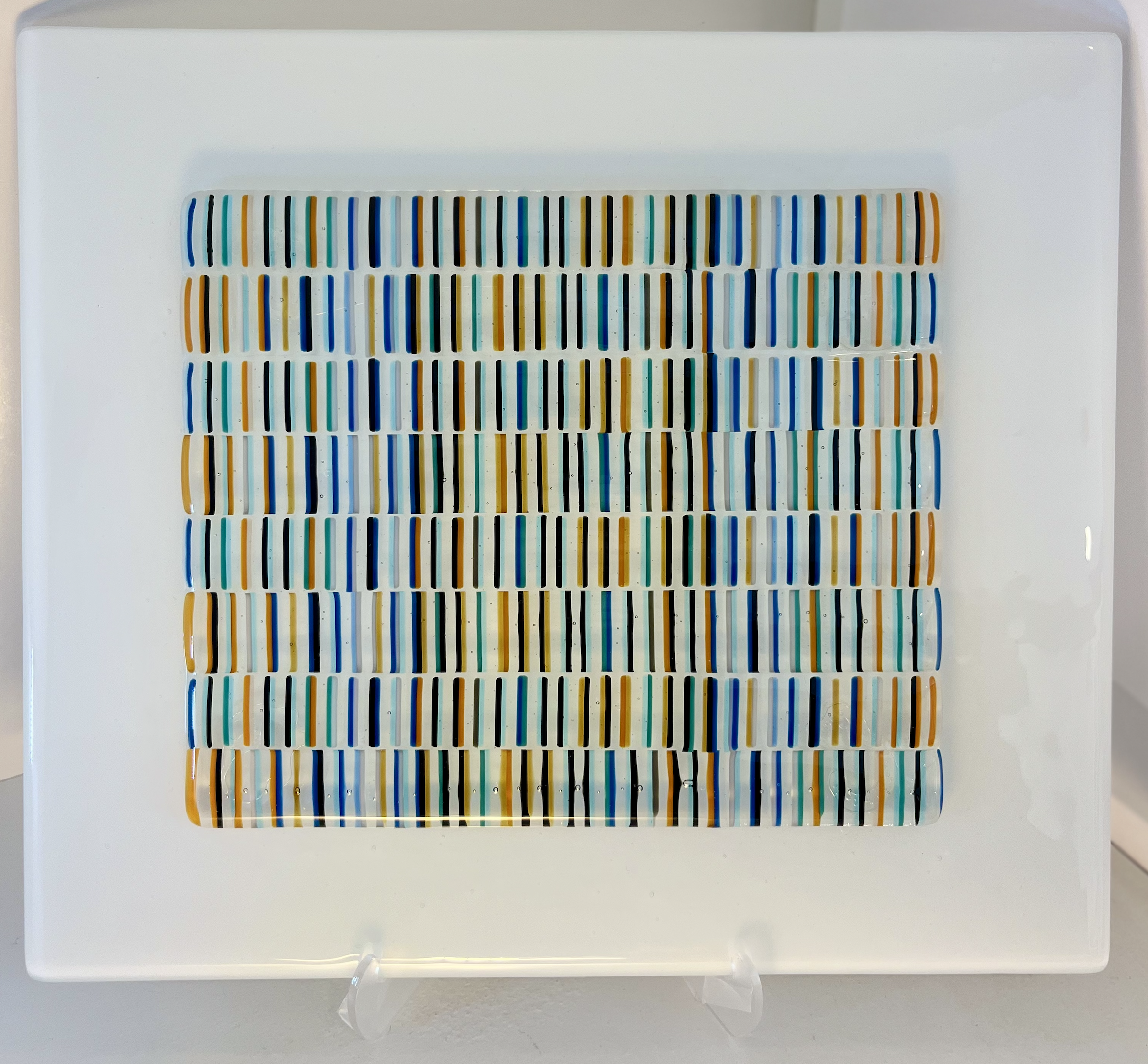 Back and Forth 
 Fused Glass

Colorful vertical lines shift in alternating rhythm, echoing the movement of life’s currents—forward, back, and always in motion.

12" x 12" Framed on White Glass 
$135