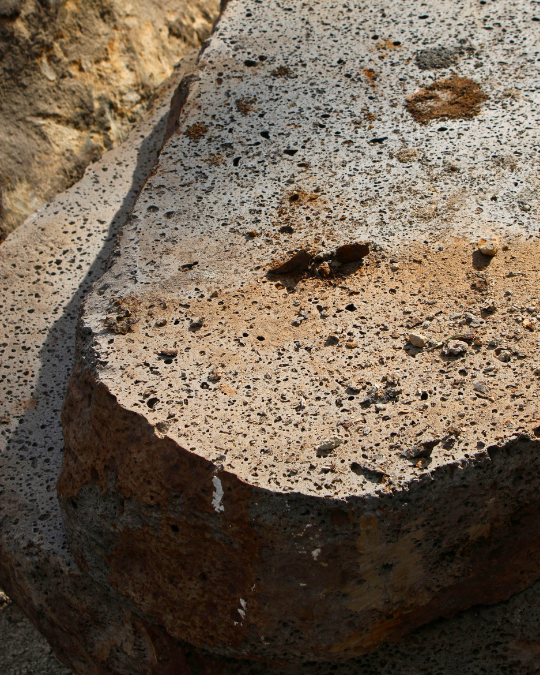 Close-up of a large, weathered rock with small pebbles and debris on its surface.