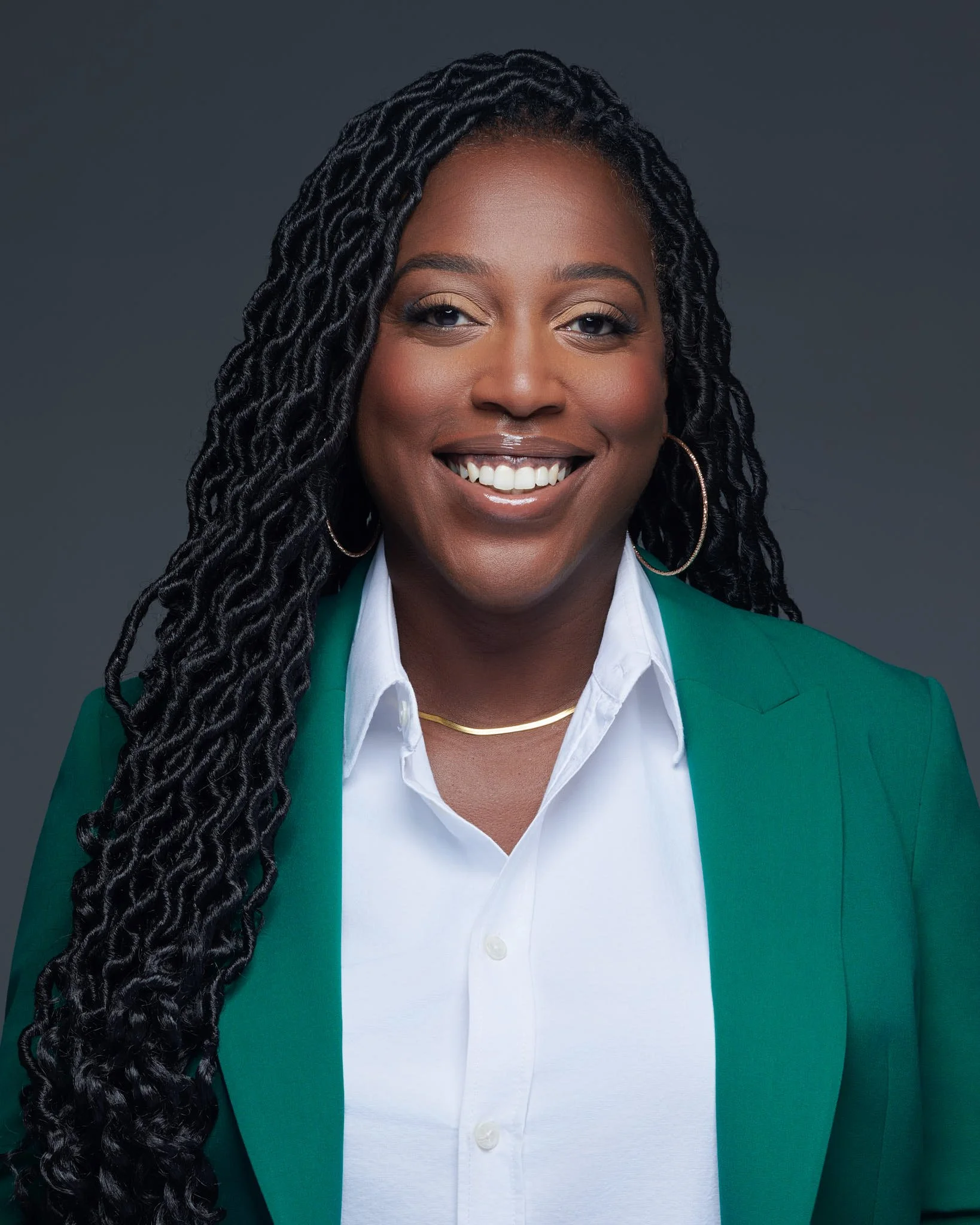 Montagnes enneigées en arrière-plan avec une maison moderne en bois sur une colline verte au premier plan.