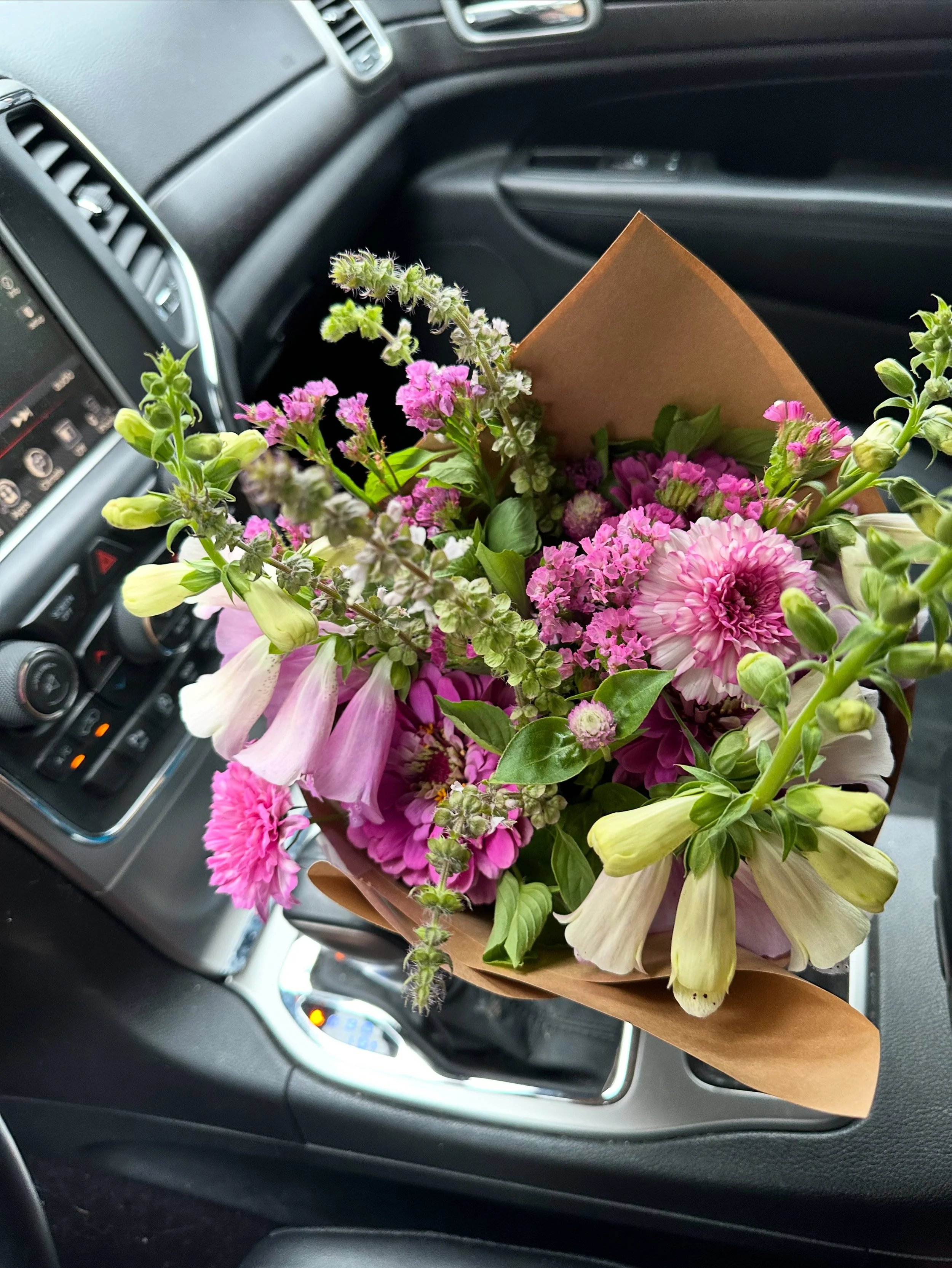 wrapped purple flower bouquet in car for delivery