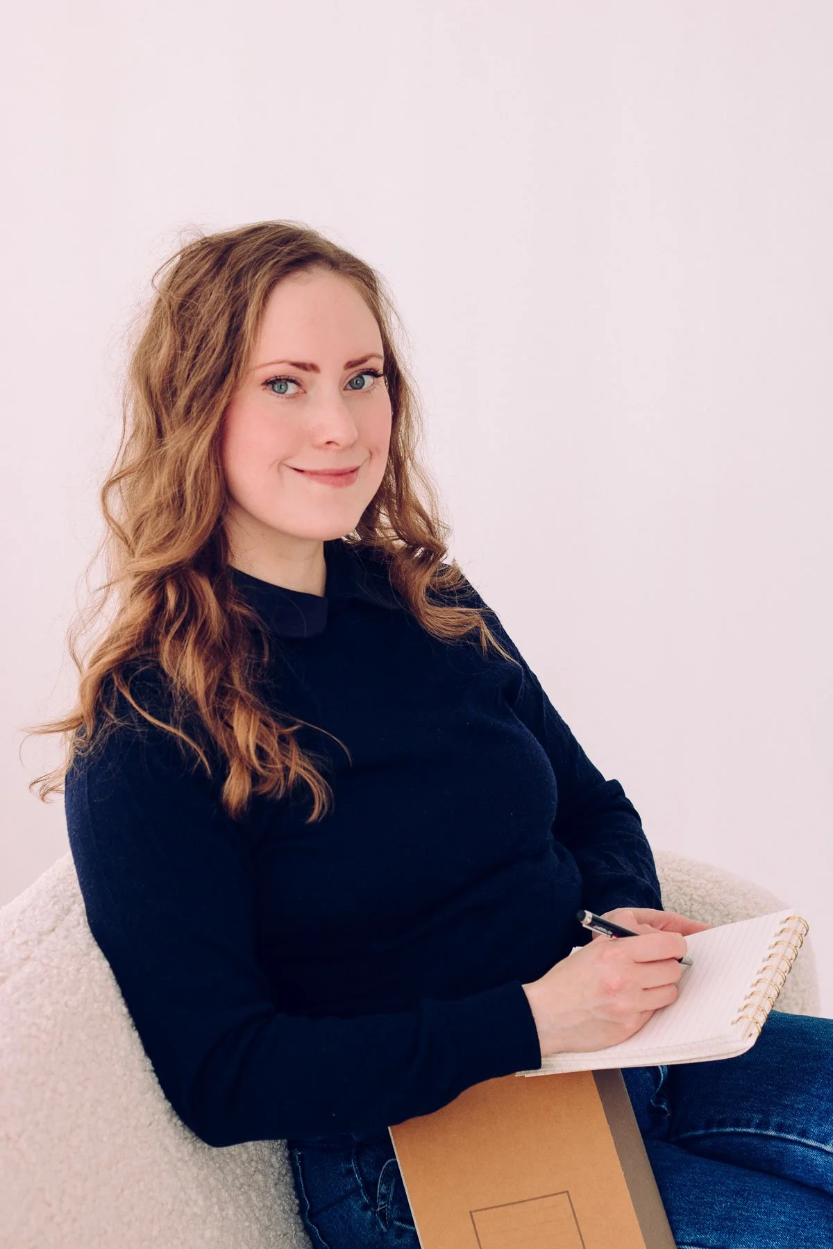 Oppivision kouluttaja istuu sohvalla, katsoo kameraan ja hymyilee.