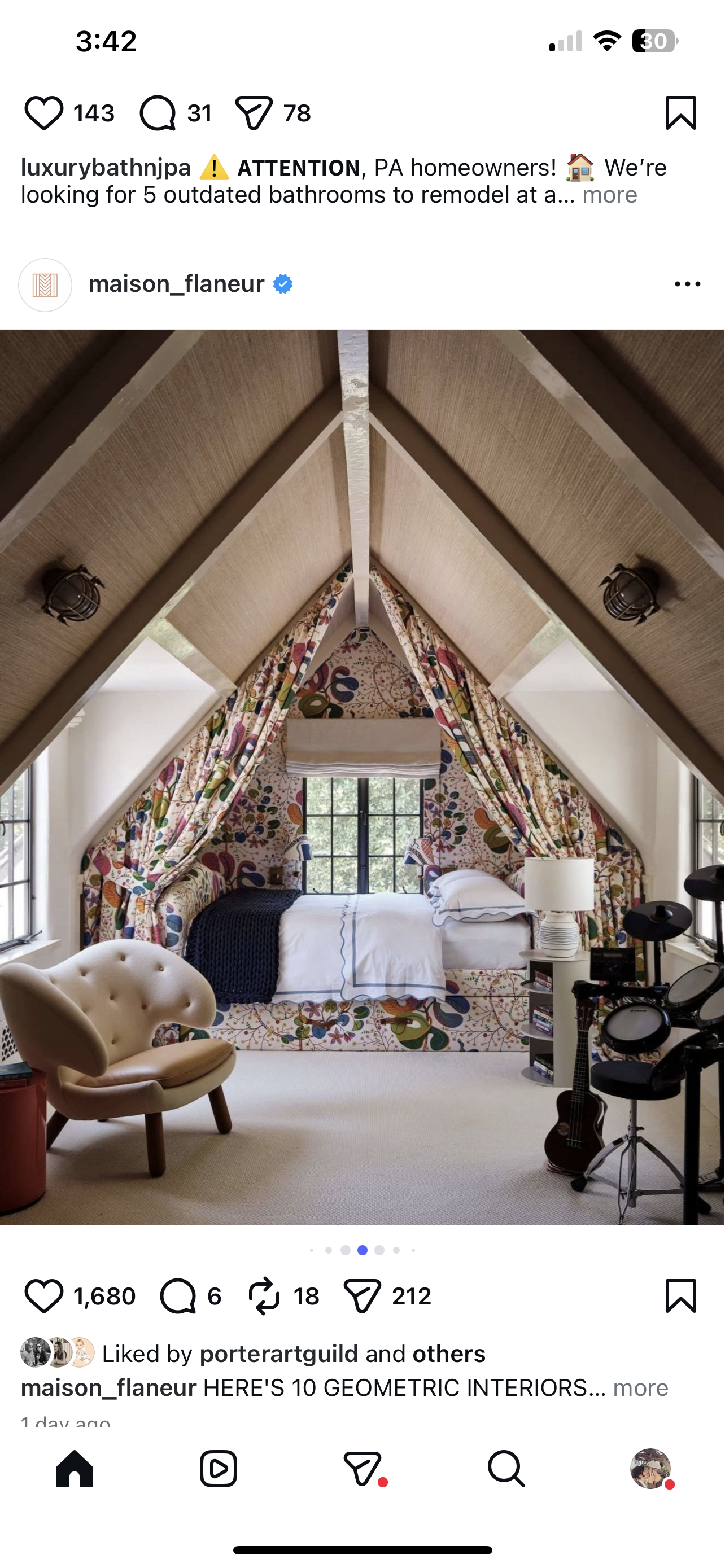 Interior of a bedroom with a bed under a window, decorated with colorful geometric patterned curtains and wall covering, a chair, a guitar, and a small table with a lamp.