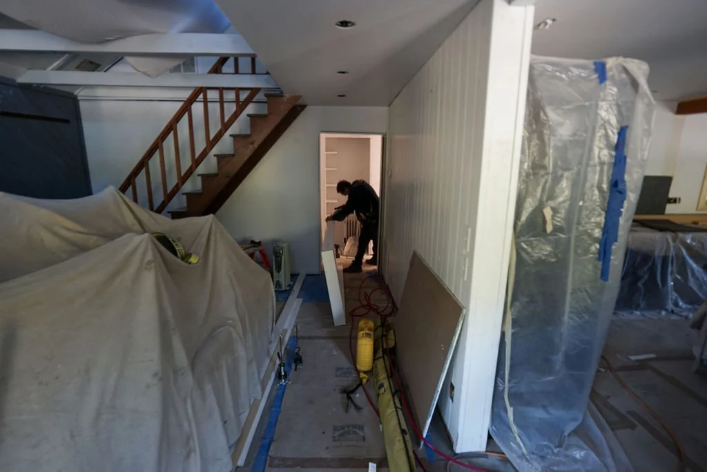 man working in room with stairs plastic and covered furniture