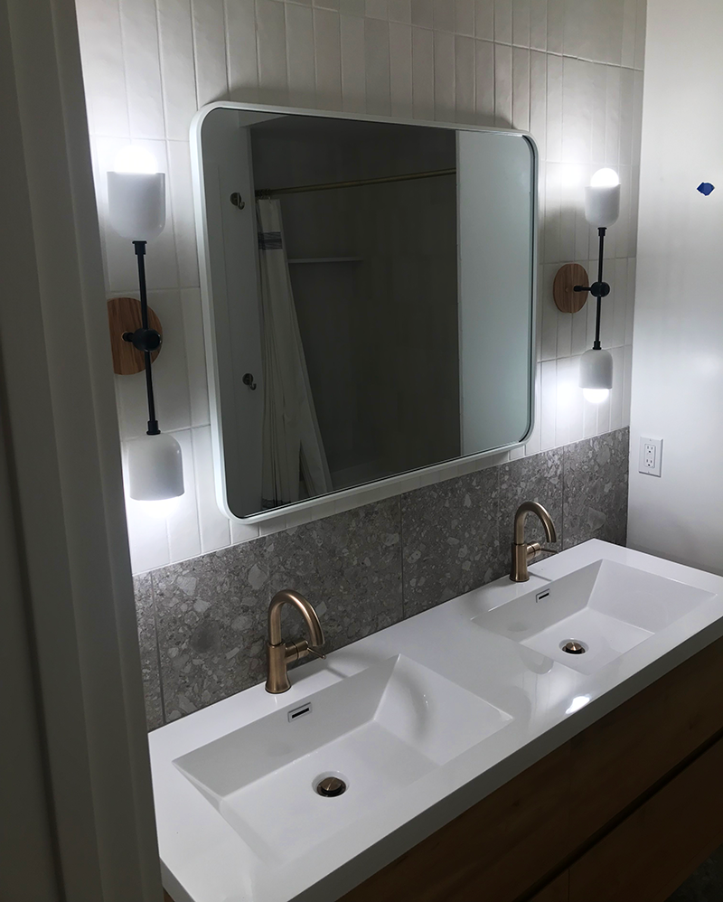 tahoe city modern bathroom remodel with double sinks gold faucets and wall-mounted lights designed by eagle bear construction