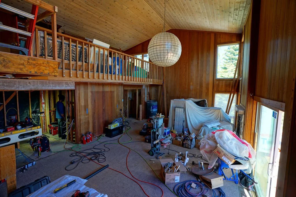 loft overlooking large room in disarray with faux wood siding