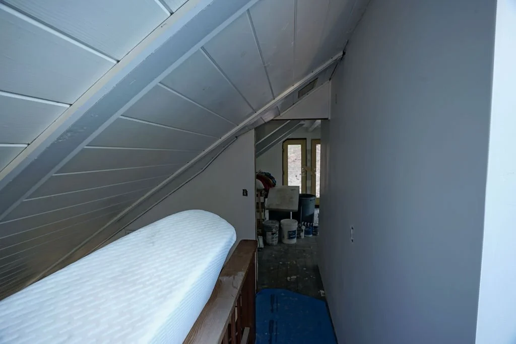 hallway with steep angled white ceiling with door