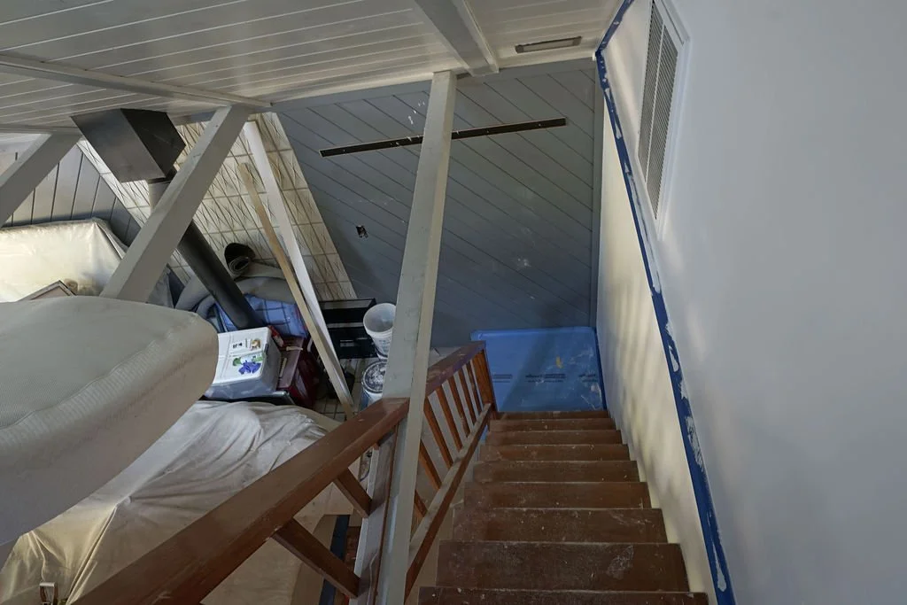 looking down steep stair to grey wall and fireplace