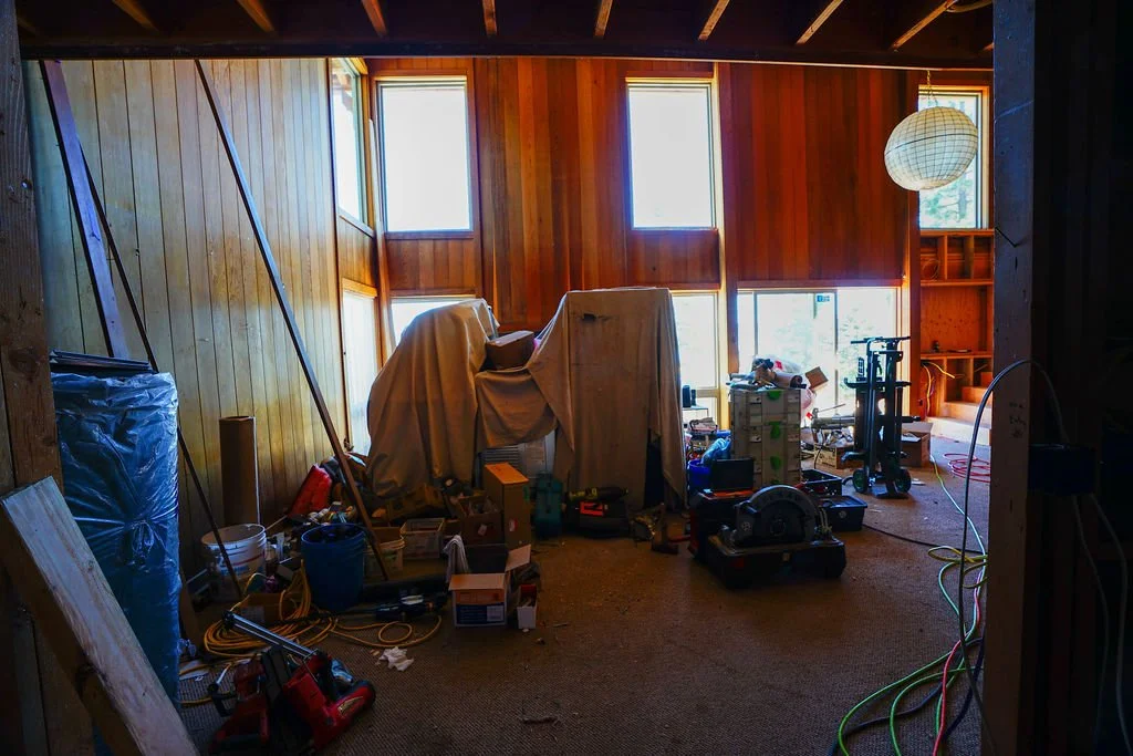 covered items in large room with old faux wood siding