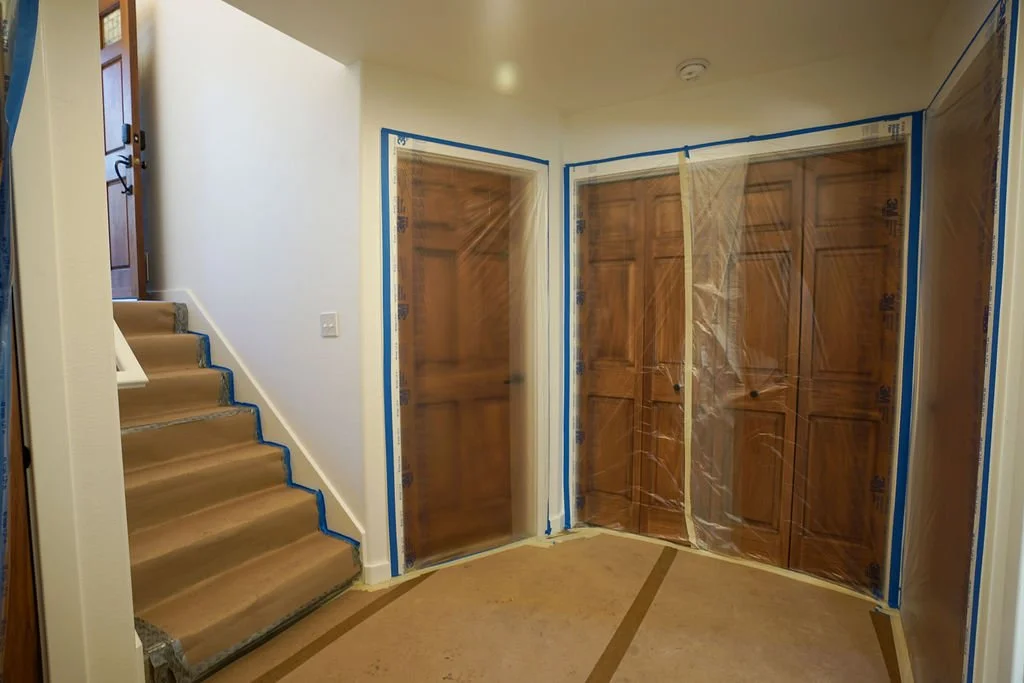 downstairs hallway with taped paper covered floor and doors