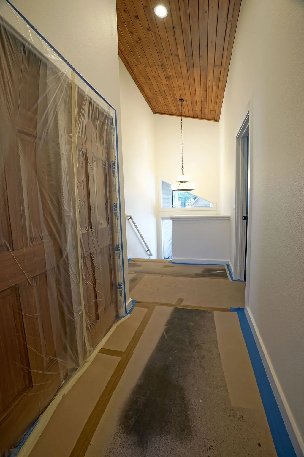 hallway with plastic covered doors and paper covered floor