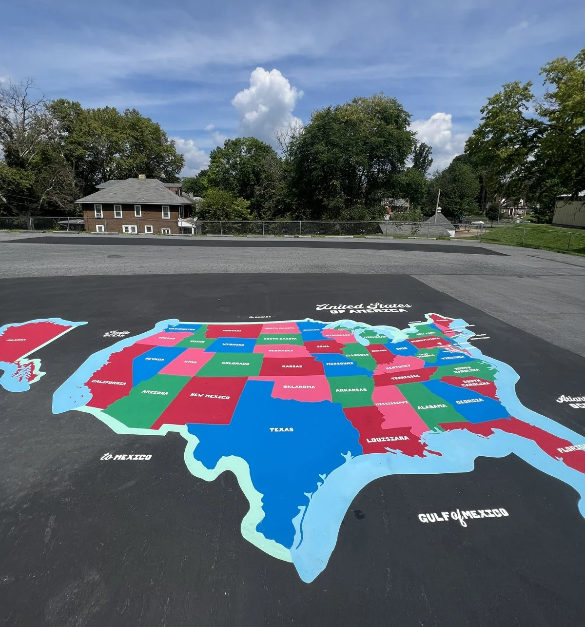 Colorful hand painted map of the United States on pavement, with state names labeled.