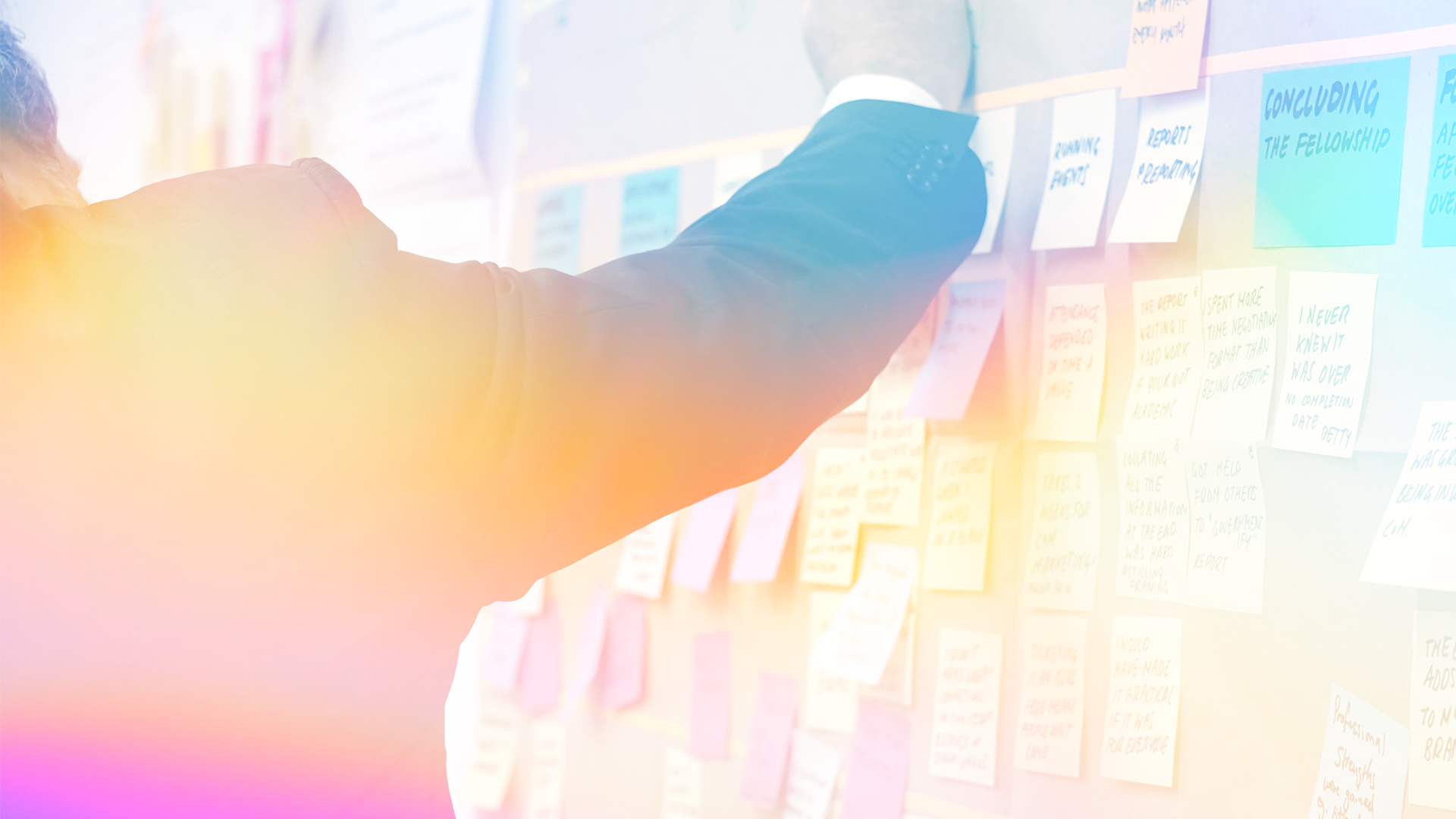 Person in suit interacting with colorful sticky notes on a wall.