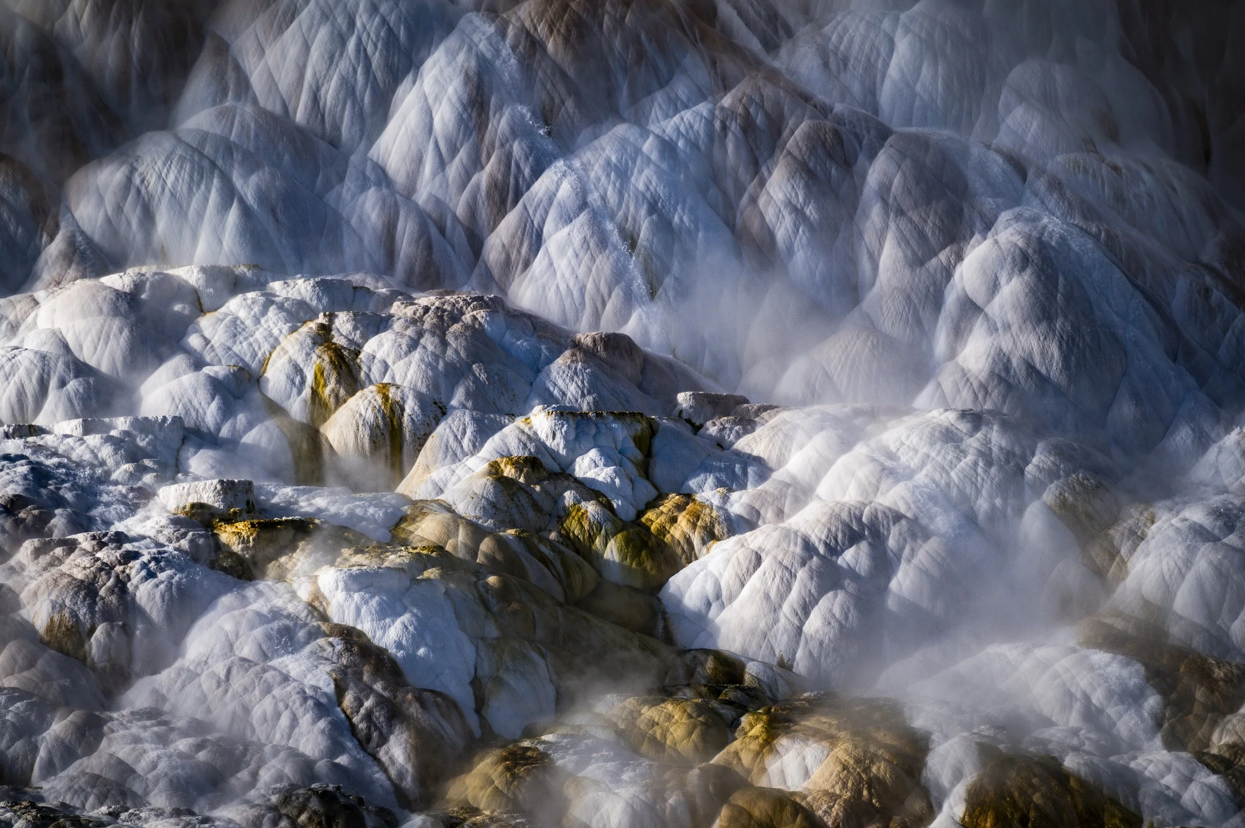 Steam rising from snow and ice-covered rocks, creating a foggy atmosphere.