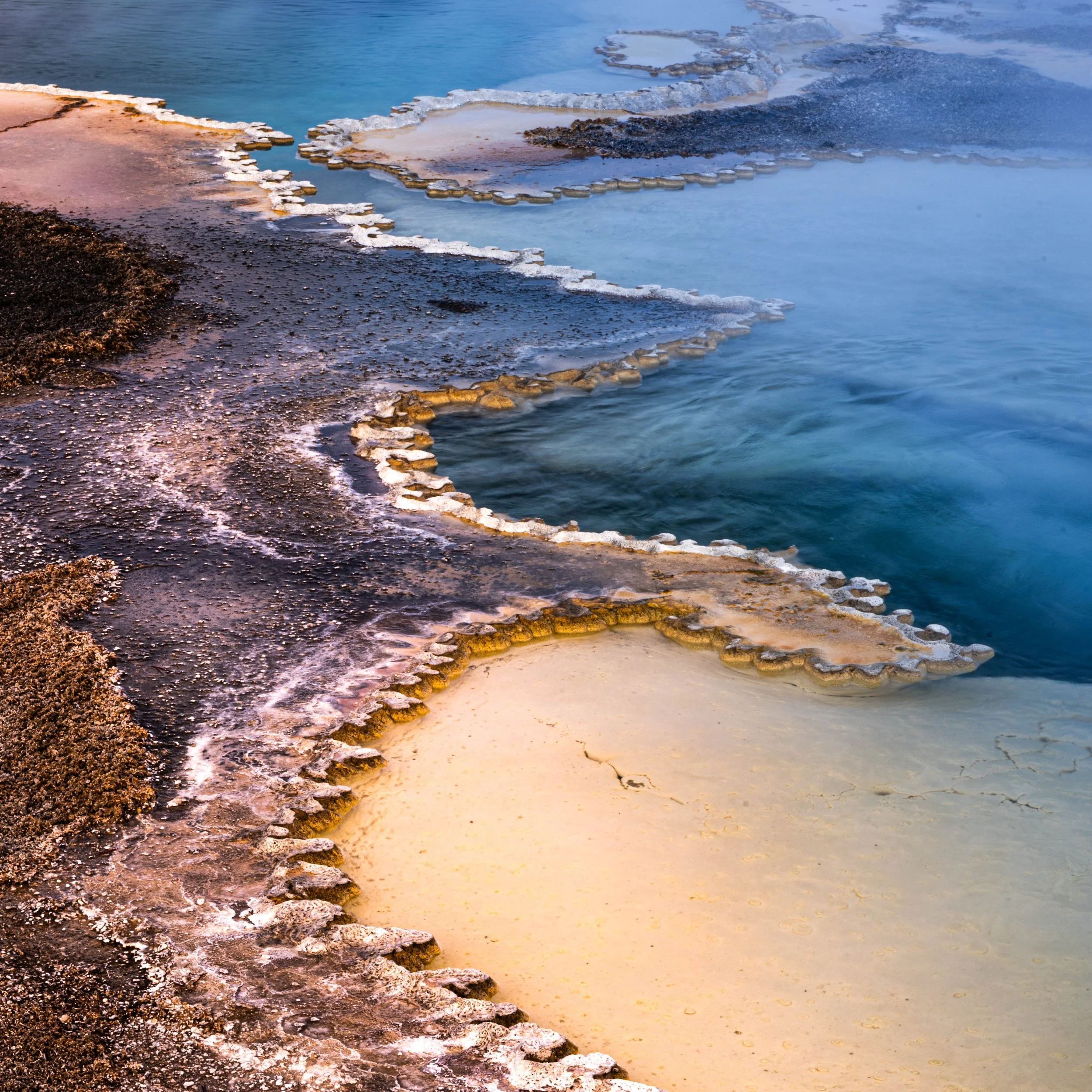 Hot springs with mineral deposits and steaming water in a natural setting.