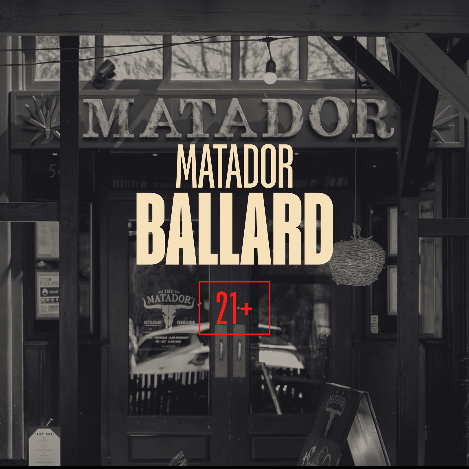 Black and white photo of the entrance of a restaurant called Matador, with a sign that reads 'MATADOR' and a smaller sign 'Matador Ballard' with a 21+ age restriction.