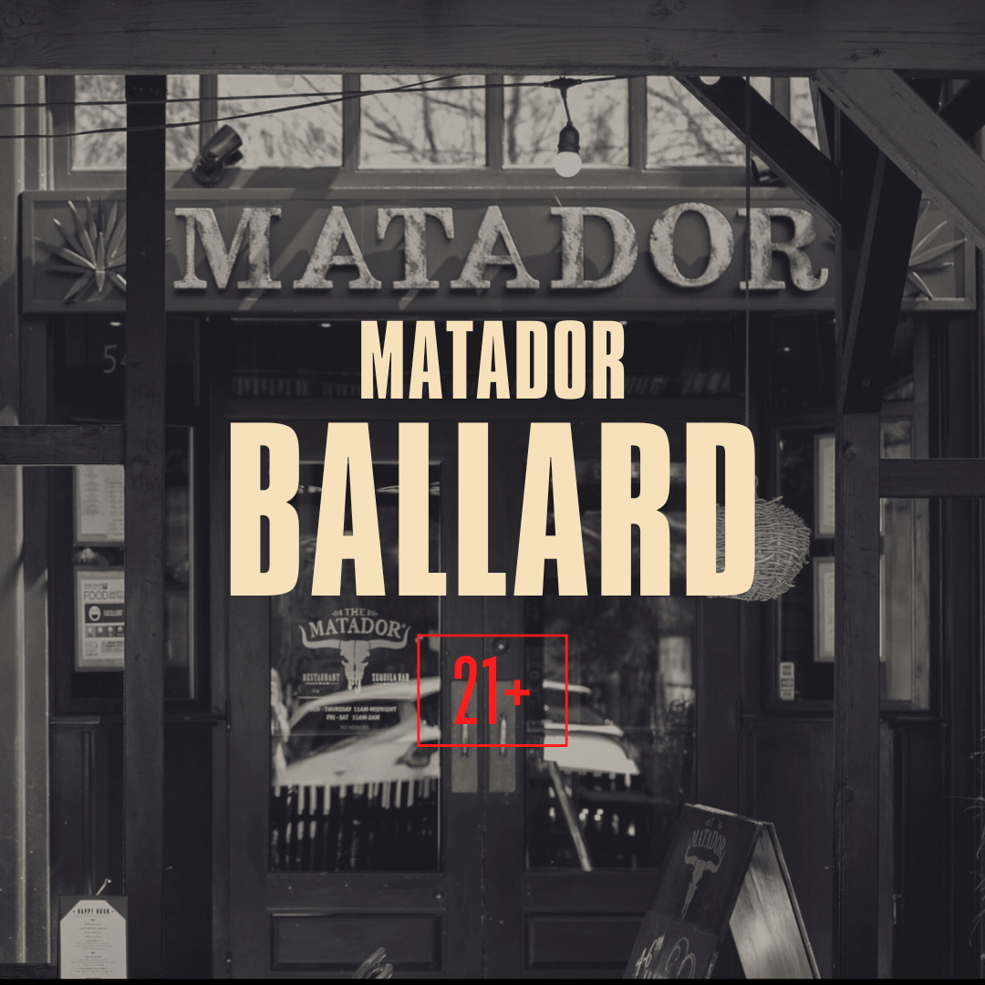 Black and white photo of the entrance to a restaurant called 'The Matador', with large signage, glass doors, and a menu board outside.