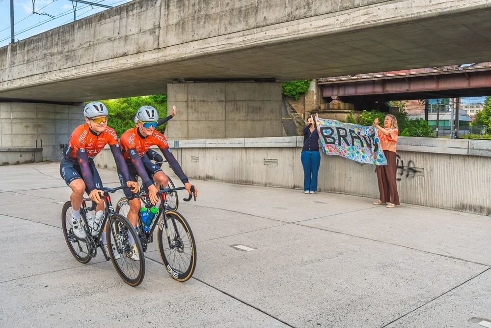 Cyclis fietsers rijden langs supporters met banner