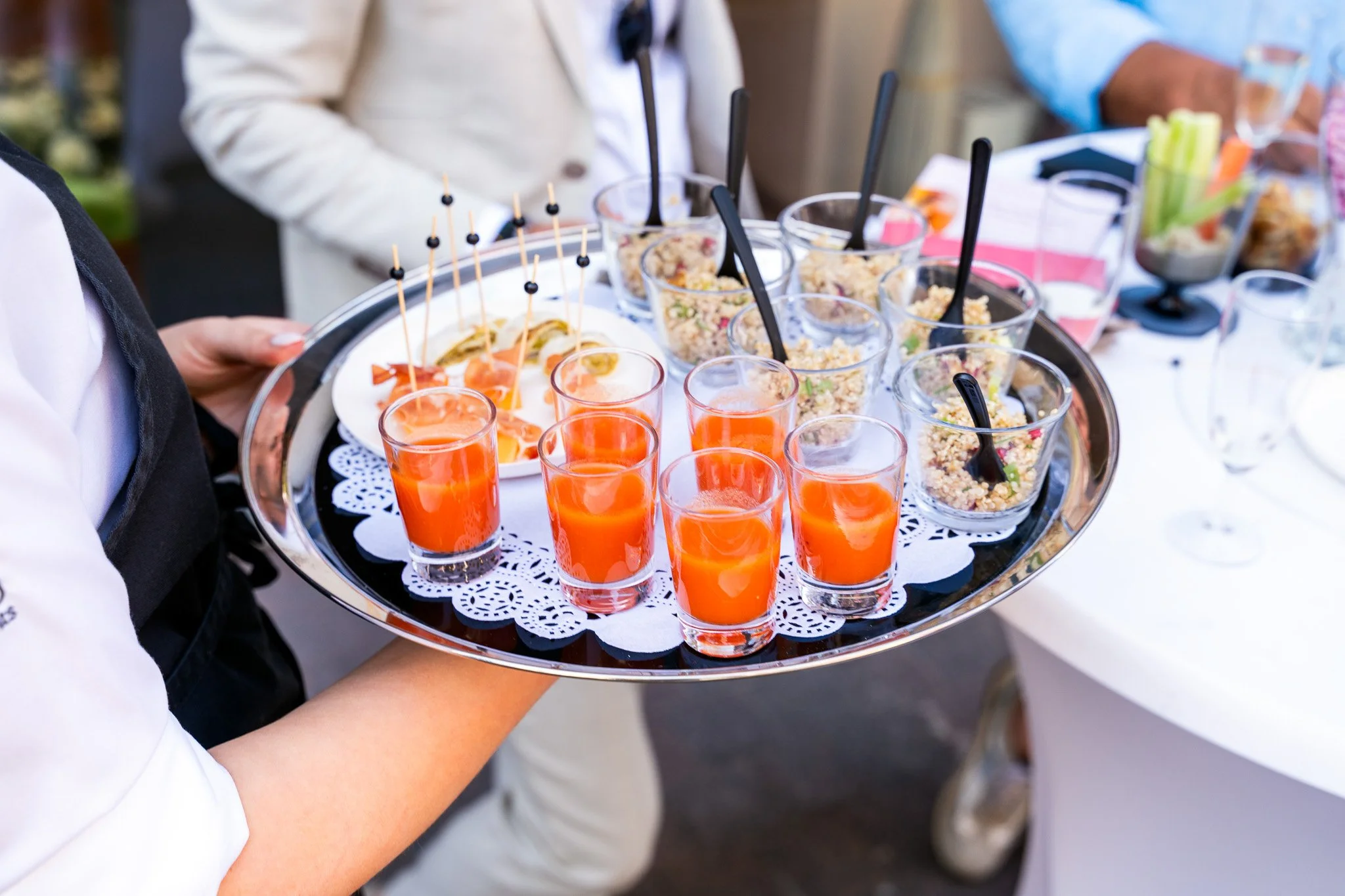 Serveerster met hapjes en oranje drankjes op een plateau tijdens de opening van Bella Dita
