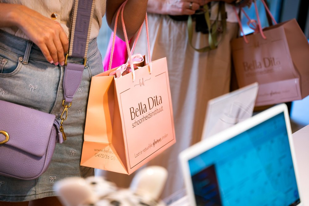 Roze Bella Dita geschenktasje in de hand van een bezoeker tijdens de opening