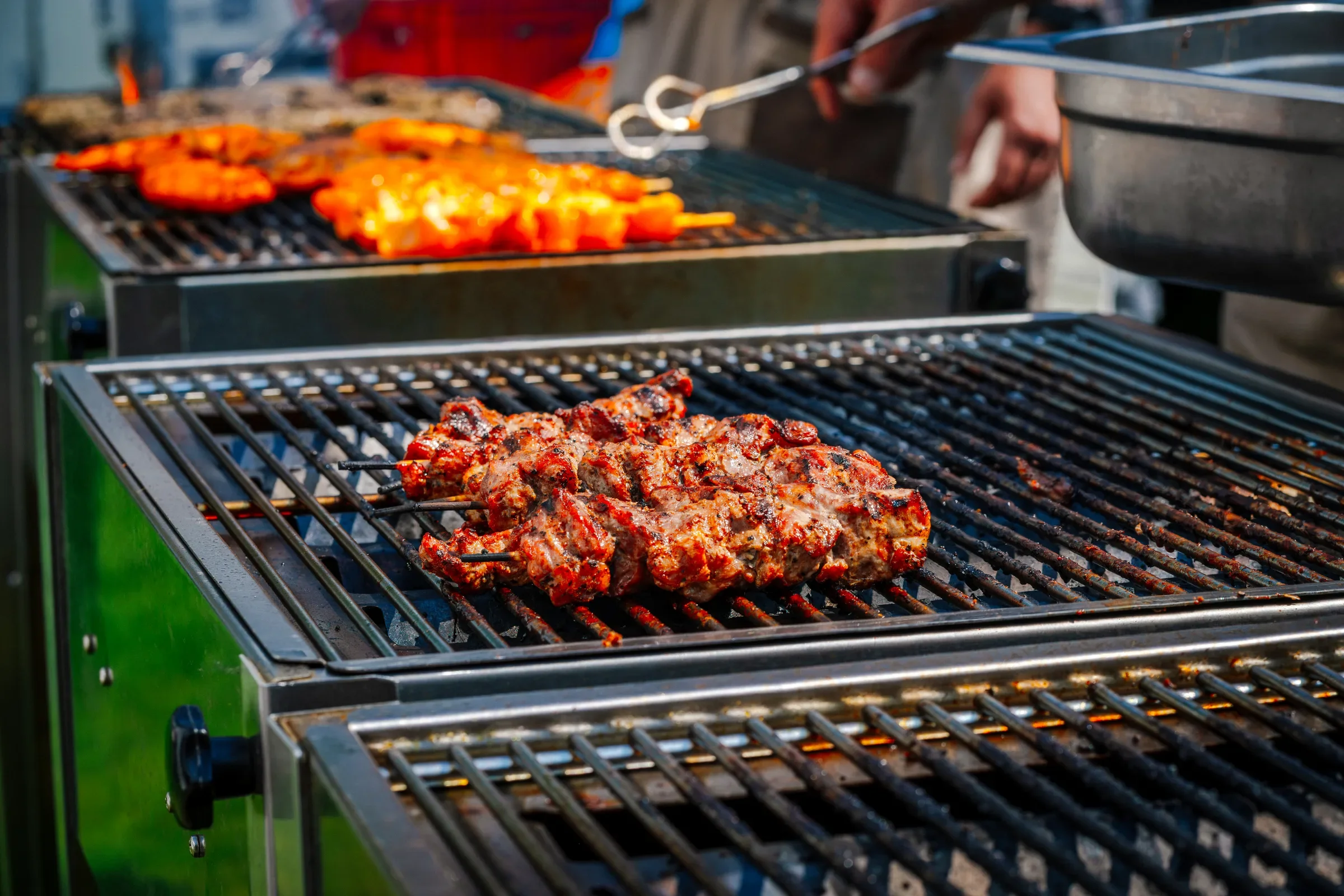 Barbecue met gemarineerde vleesspiezen en gegrilde vleeswaren op grillroosters.