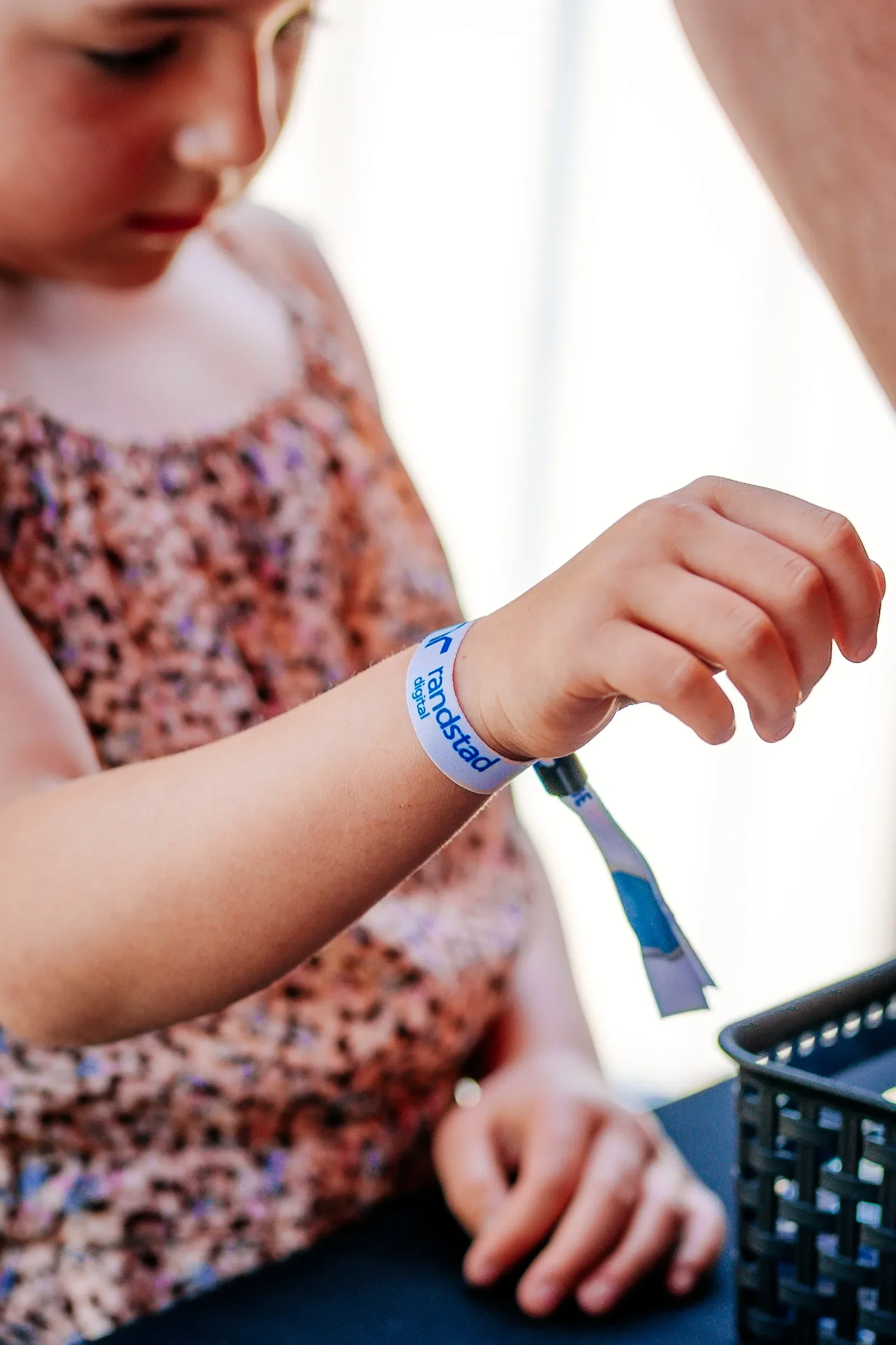 Meisje met een armband dat zegt 'Proud to be vaccinated' dat haar pols omwikkelt, en ze houdt een apparaat vast terwijl ze zich laat vaccineren.
