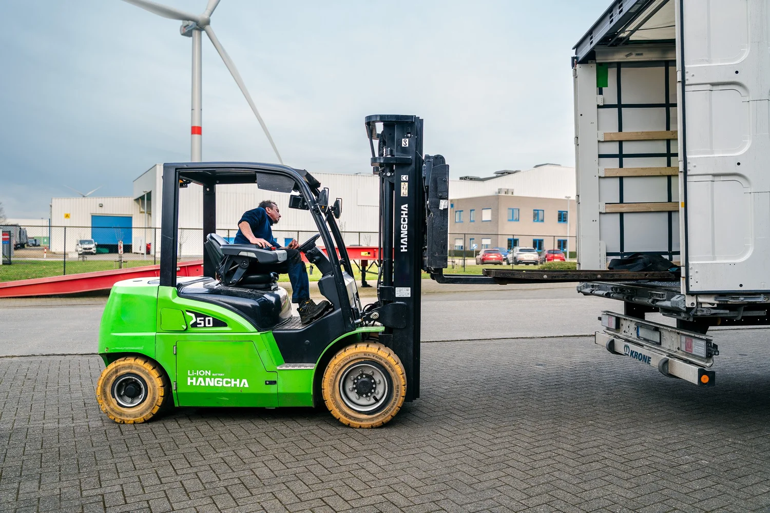Groene heftruck naast een vrachtwagen