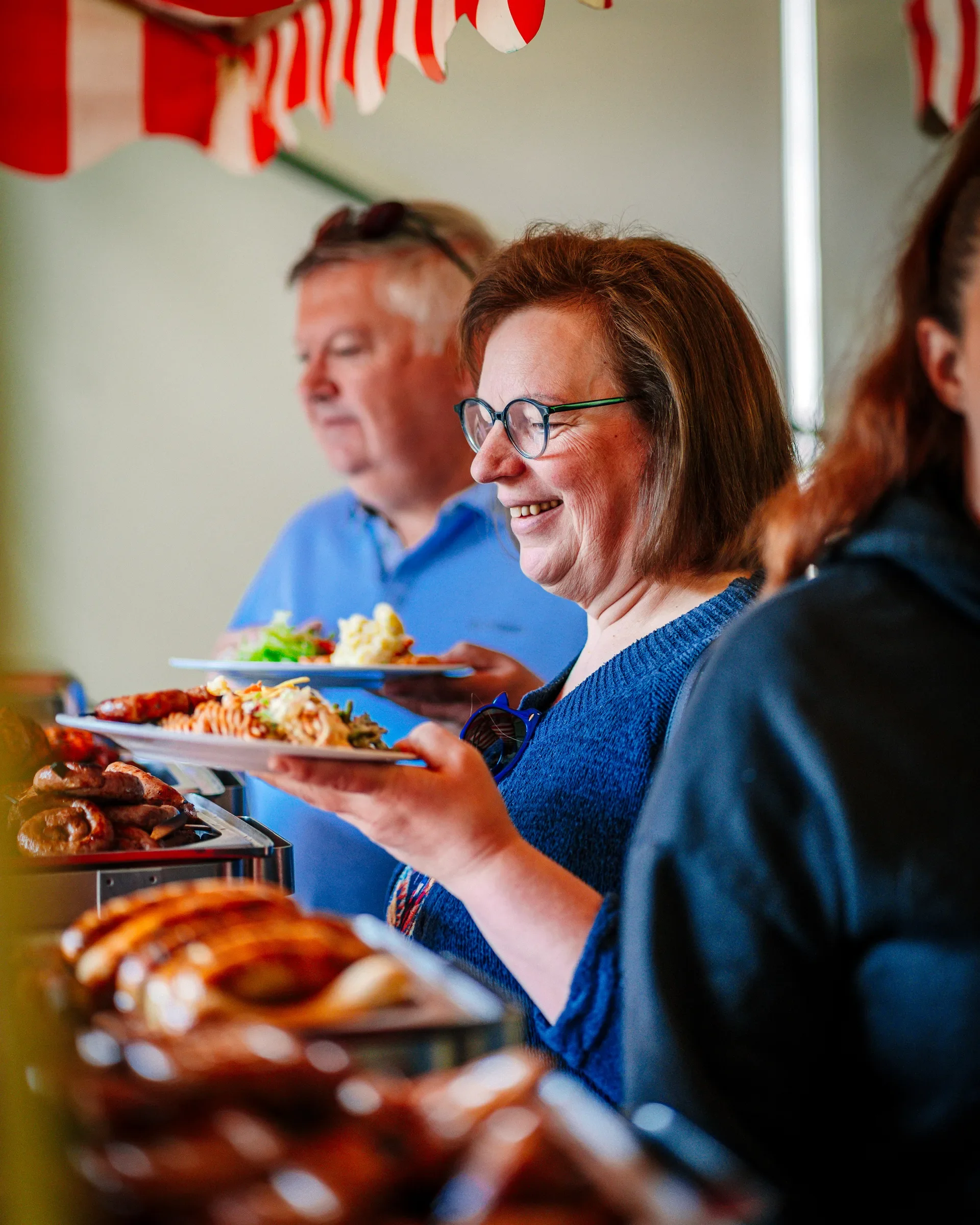 Mensen die genieten van een buffet met verschillende gerechten, waaronder vlees, vis en bijgerechten, in een gezellige evenementenruimte.