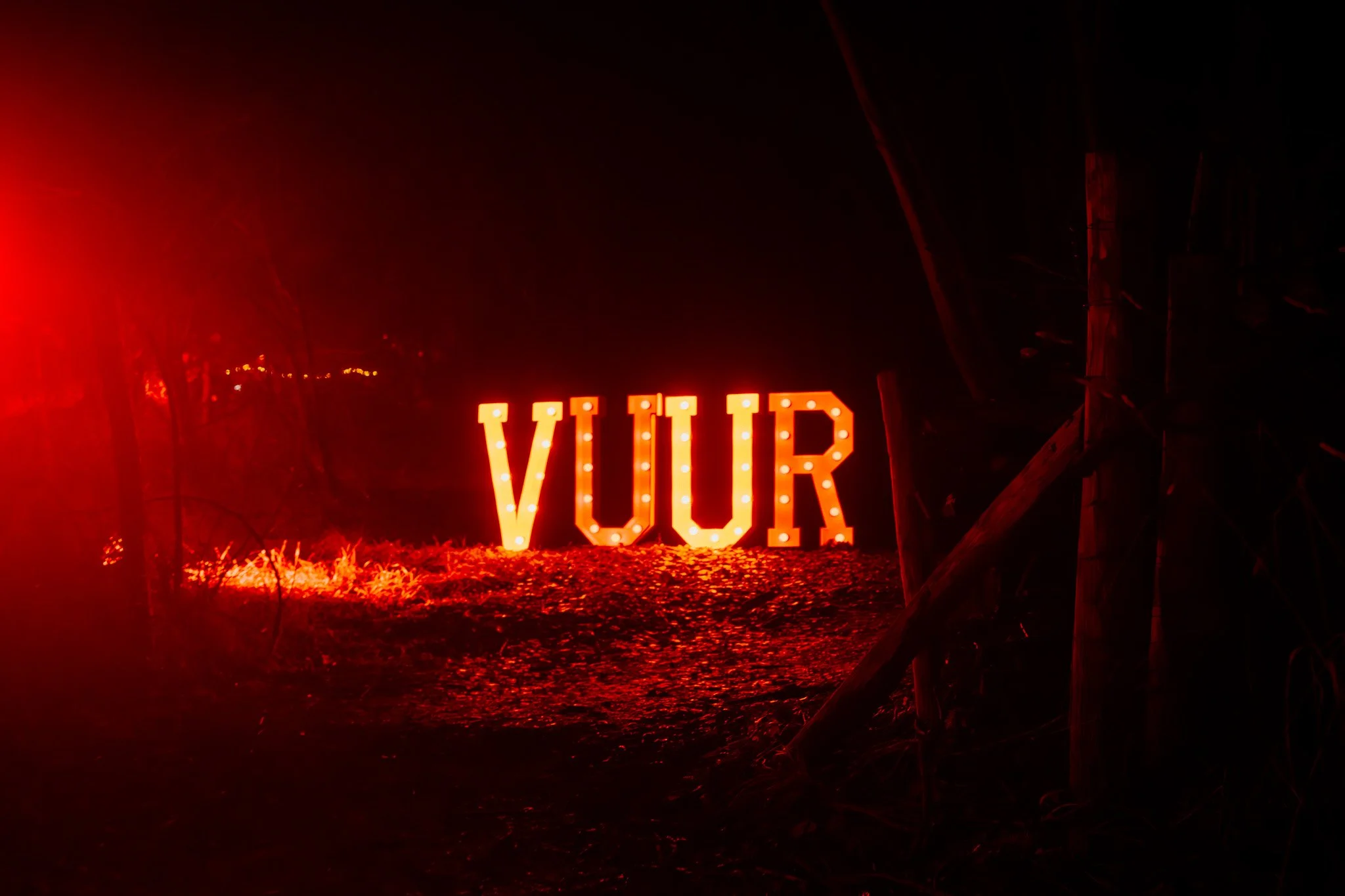 Verlichte letters die VUIR vormen, buiten bij nacht met rode verlichting en bomen rondom.