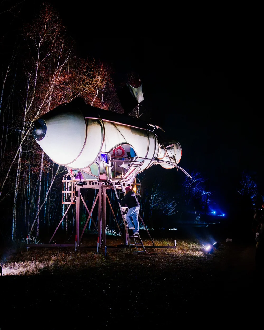Foto 100: Luchtgedeelte van Luminoctis met gele lichtaccenten, ruimtelijke objecten en open nachtbeeld.