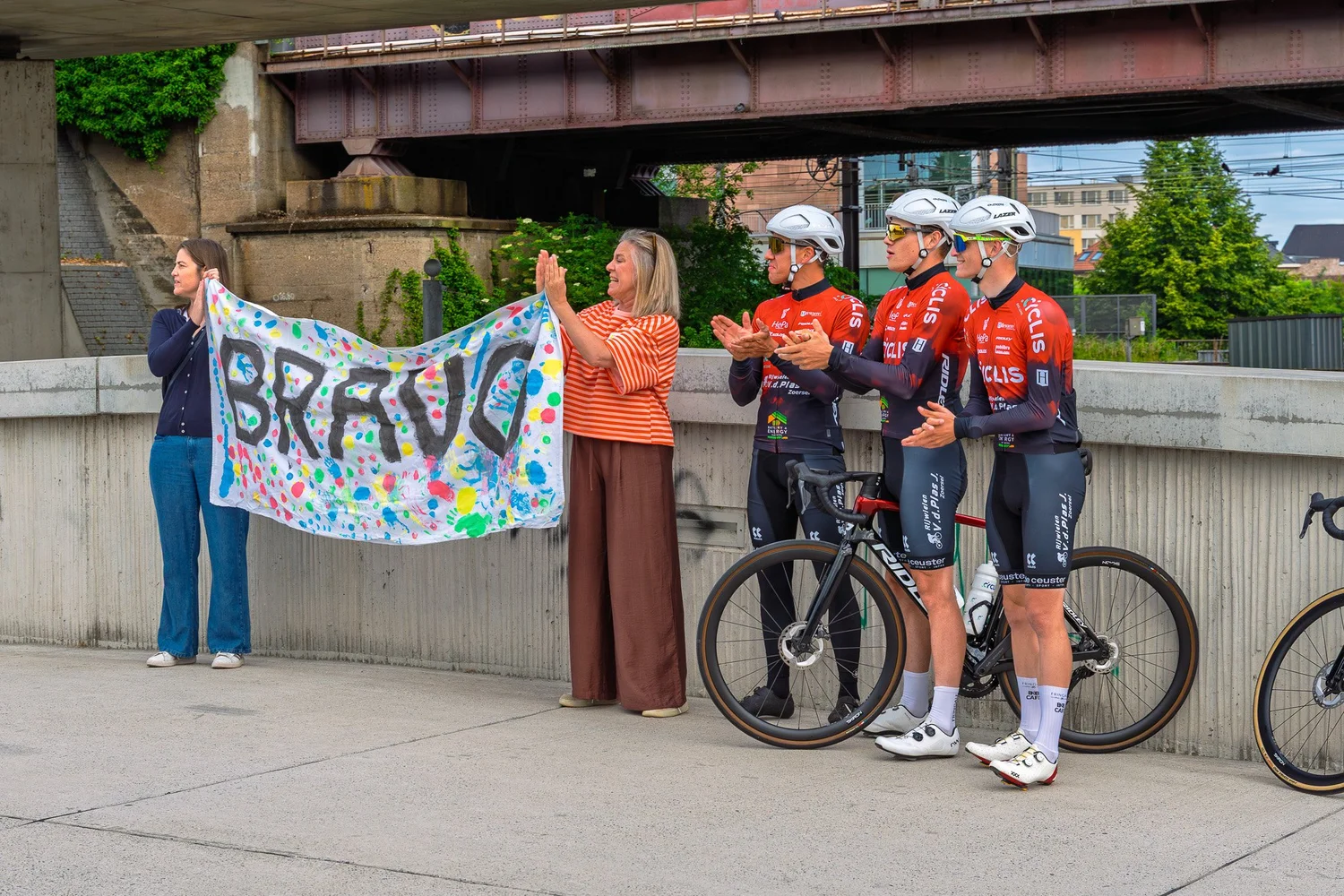 Cyclis team en supporters met Bravo spandoek