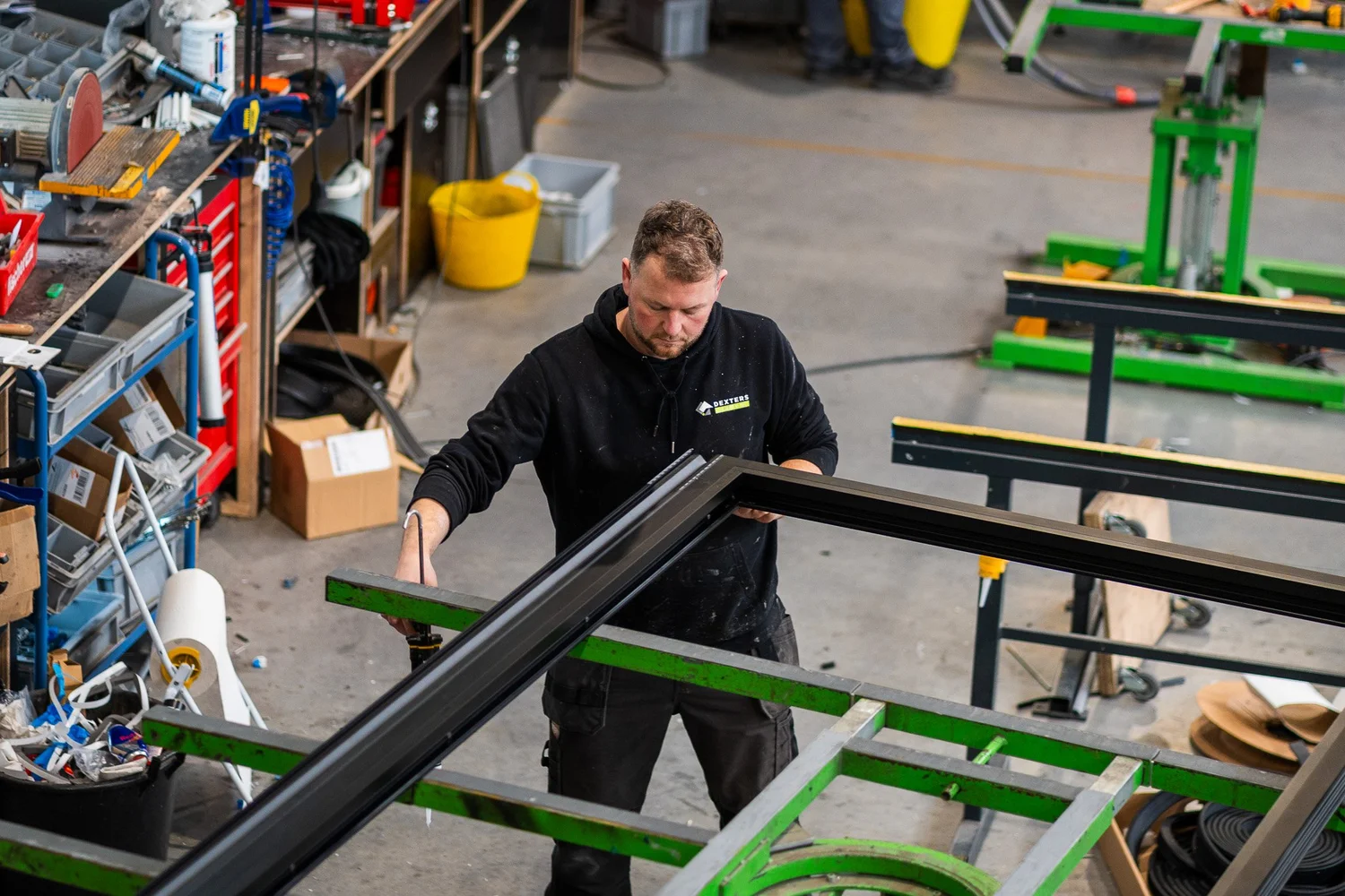 Medewerker aan een werkbank tijdens de raamproductie bij Dexters