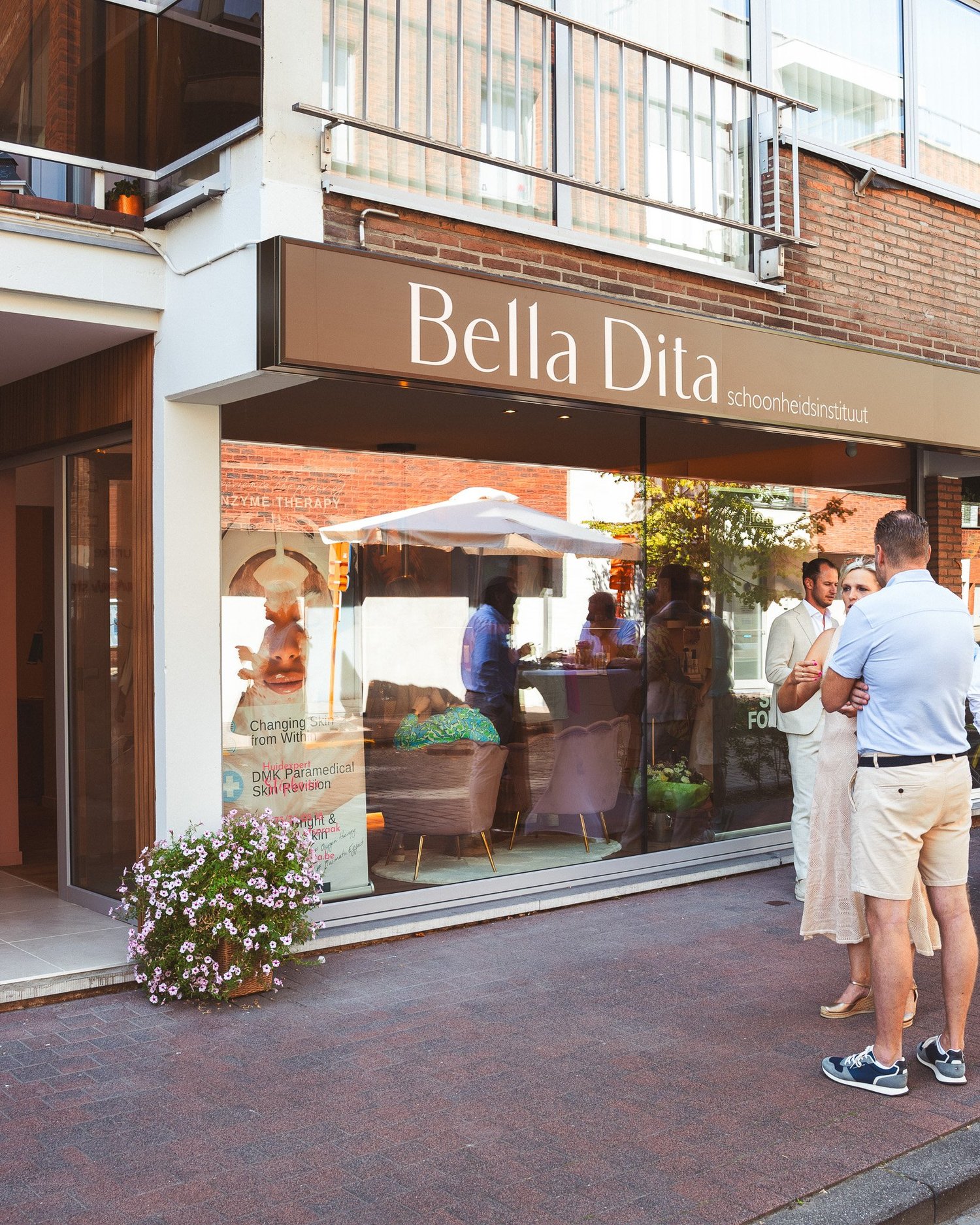 Bella Dita gevel met reflecties in de ramen en bezoekers aan de inkom