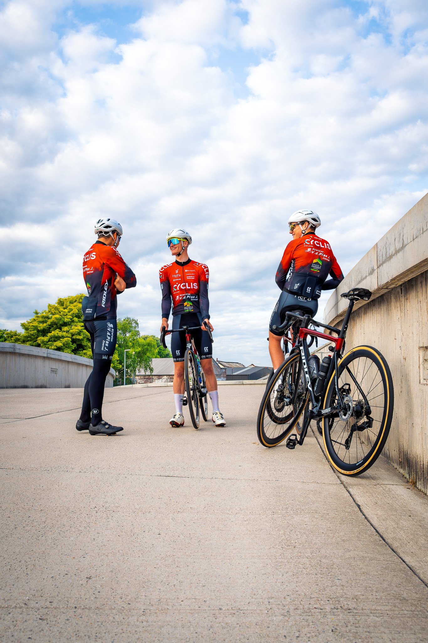 Cyclis Van Den Plas fietsteam in oranje wielertenues onder een bewolkte hemel