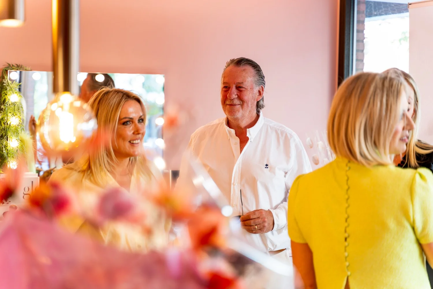 Blije gasten binnen in Bella Dita met warm licht en bloemen op de voorgrond
