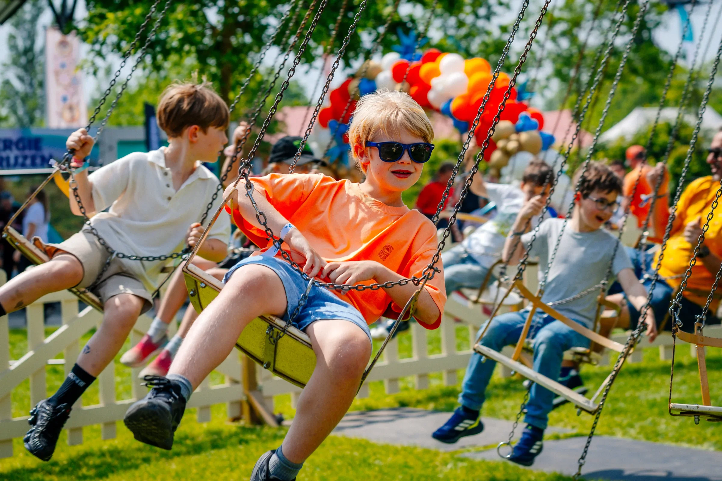 Kinderen op een trekschommel in een park op een zonnige dag.