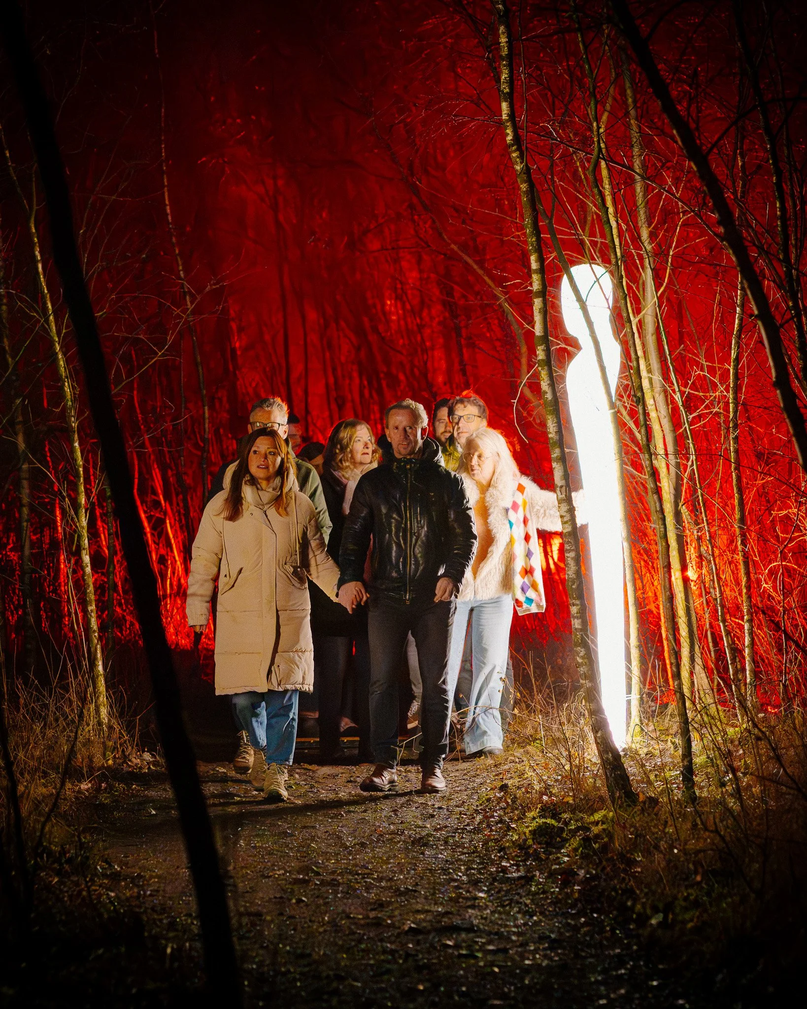 Mensen wandelen door een donker bos met wandverlichting tijdens de avond of nacht.