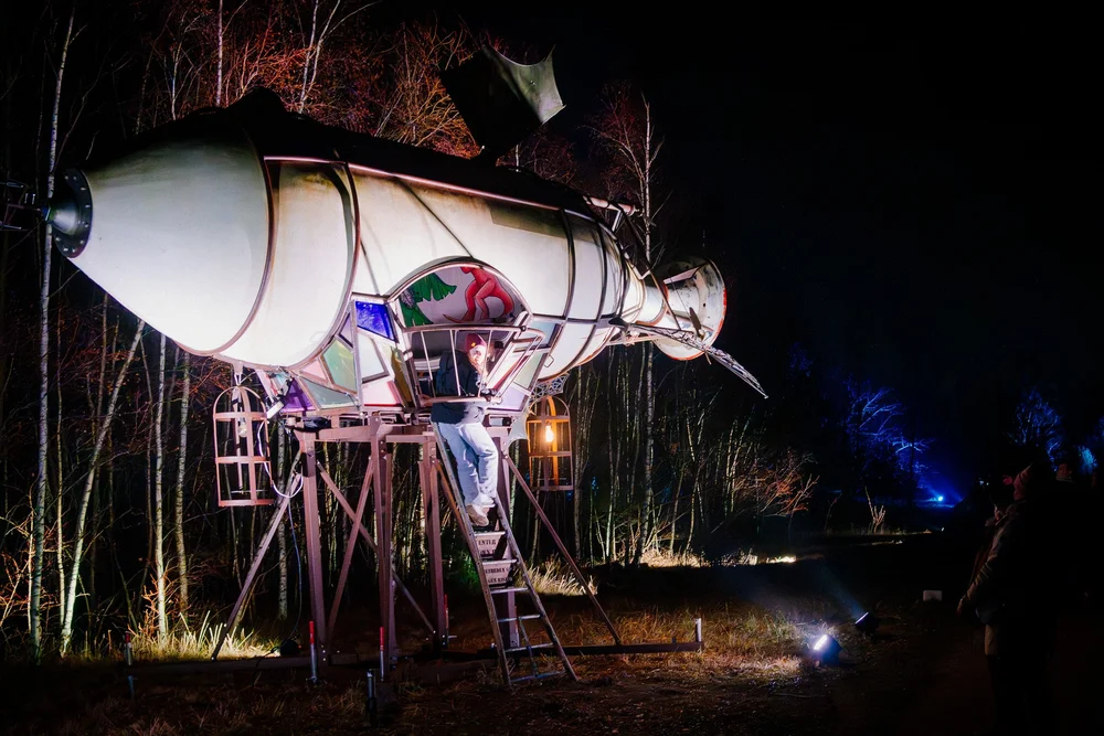 Foto 101: Luchtgedeelte van Luminoctis met gele lichtaccenten, ruimtelijke objecten en open nachtbeeld.
