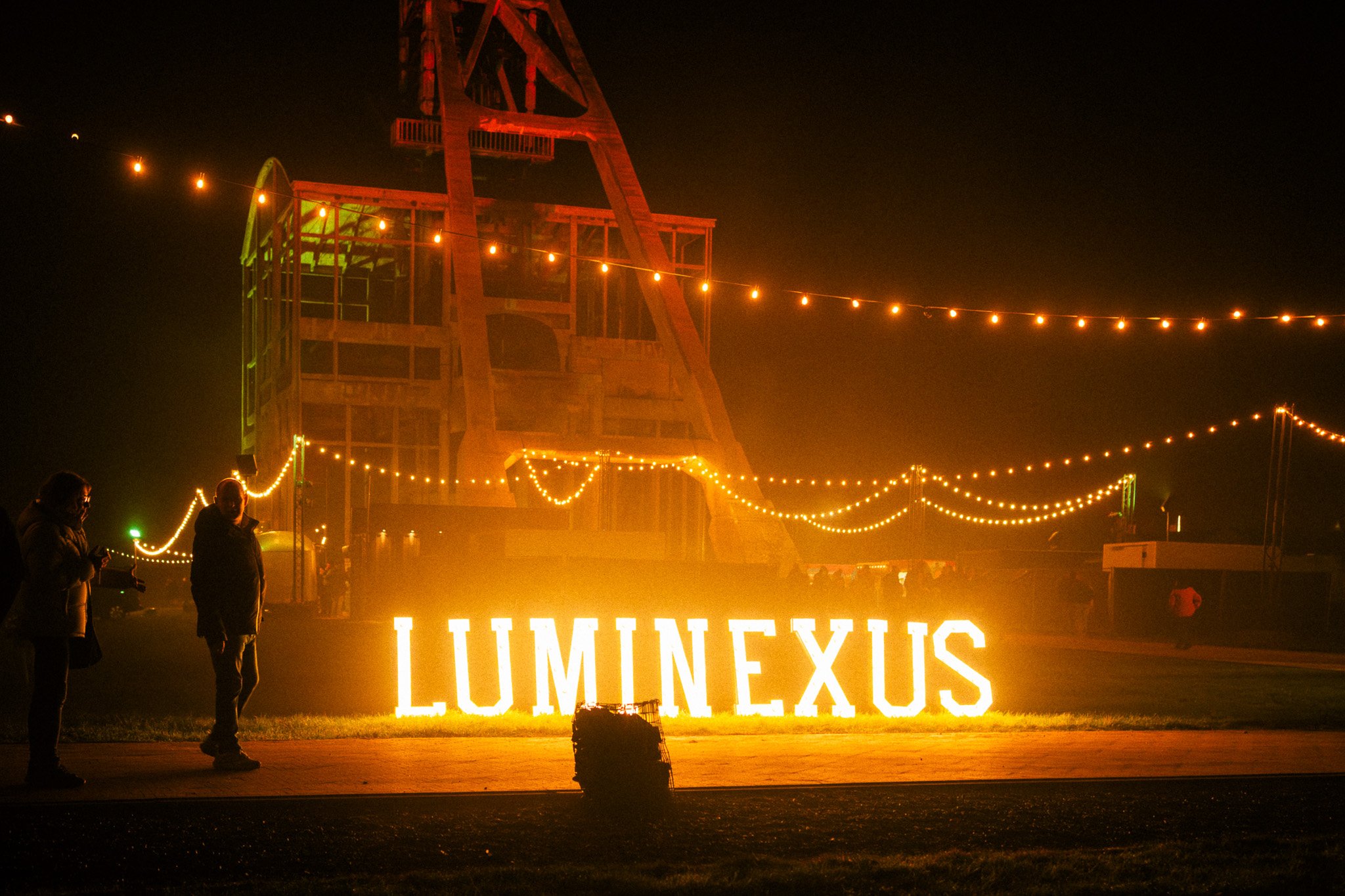 Verlichte ingang van een evenement in Mexico met grote letters die 'LUMINEXIS' spellen, omringd door kerstverlichting en metalen structuur.