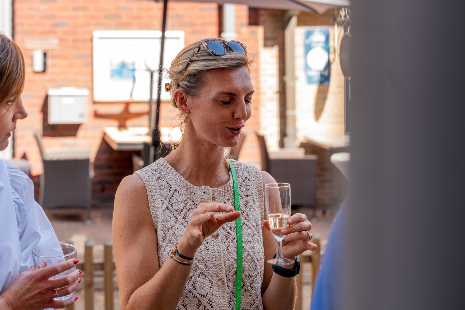 Bezoeker met champagneglas in gesprek tijdens de opening van Bella Dita