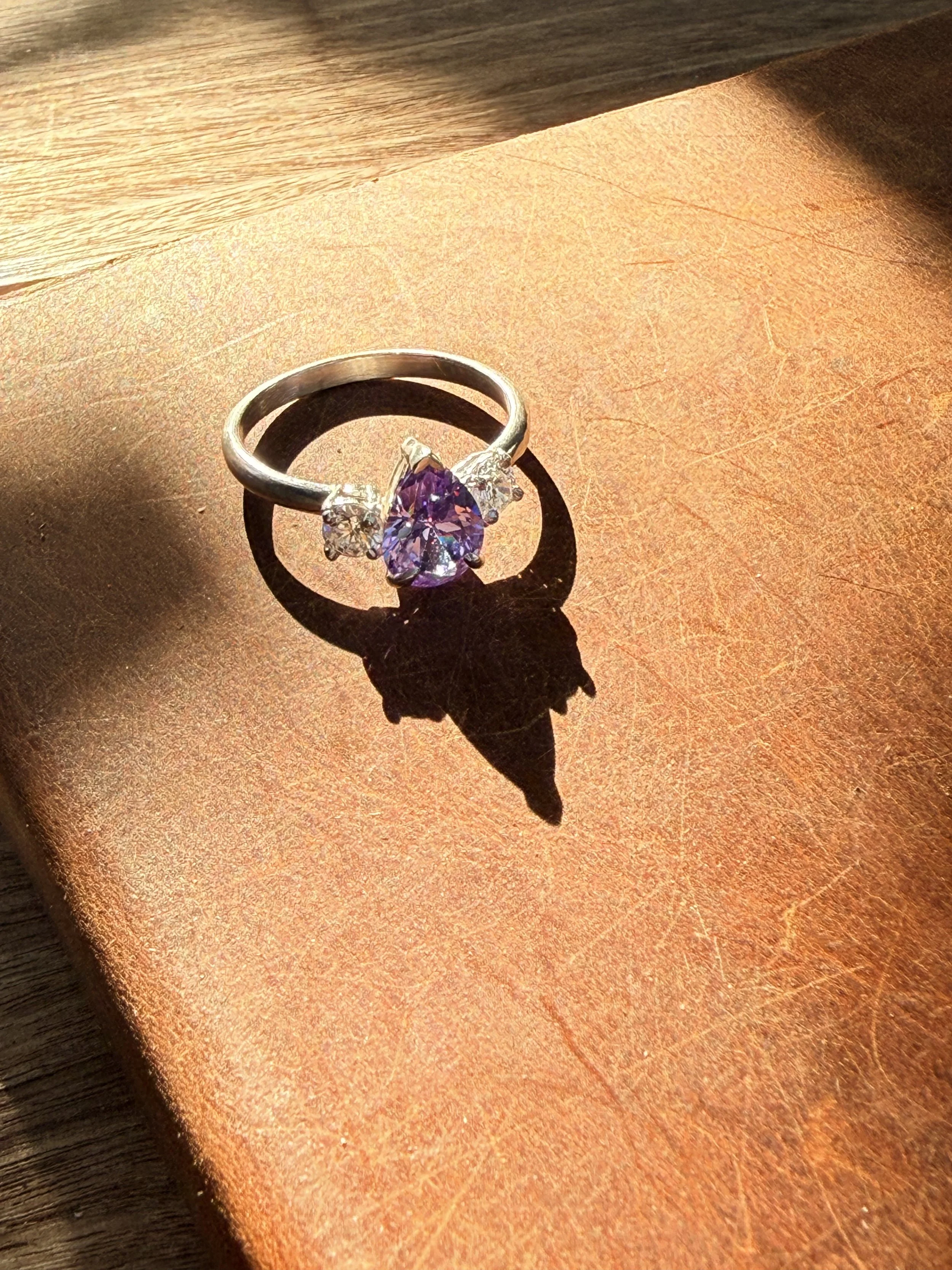 Cast sterling silver ring, prong-set matching side CZ side stones, amethyst pear-shaped center stone. 