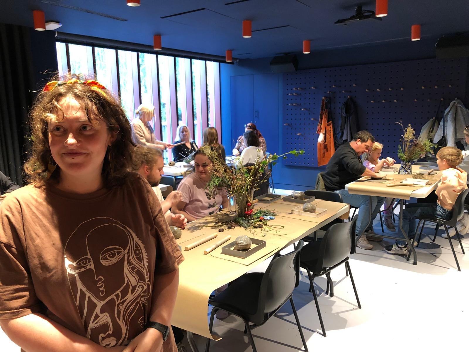 People gathered around a table in a creative workshop or class, working on arts and crafts projects with natural materials and decorative items.